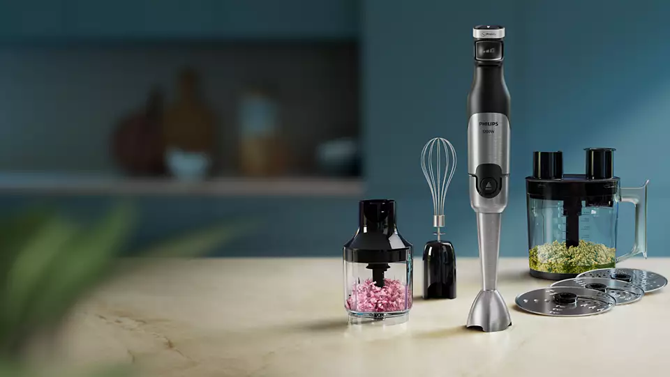 Handmixer, Schneebesen und Zerkleinerer auf einem Tisch. Küchenhintergrund.