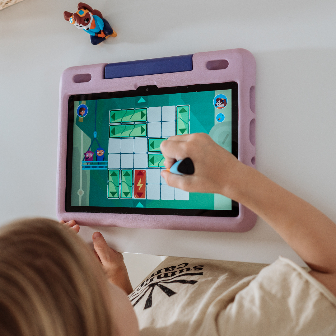 Ein Kind benutzt ein Tablet mit lila Hülle. Ein Spiel wird mit farbenfrohen Grafiken angezeigt.
