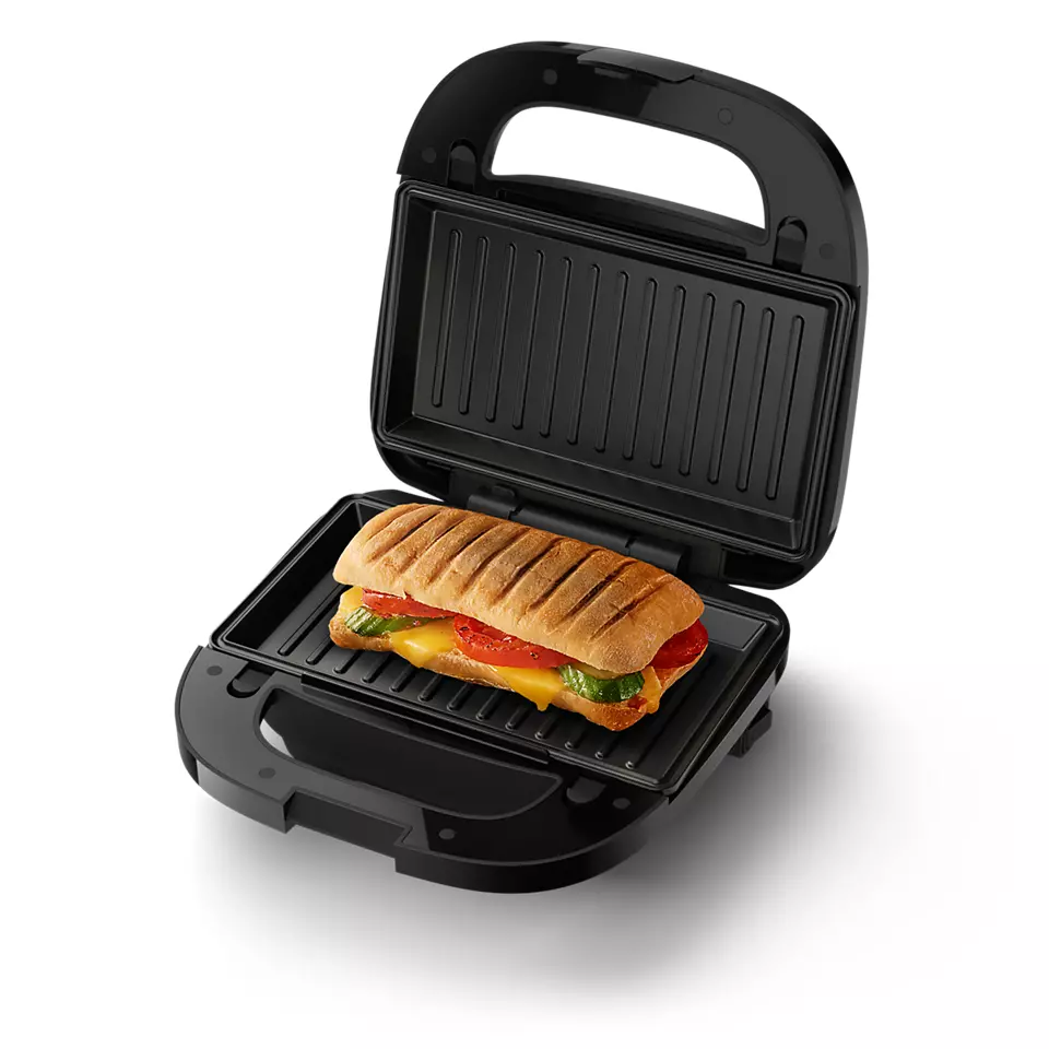 Schwarzer Sandwichmaker mit einem gegrillten Sandwich, das Käse, Tomaten und Pesto zeigt.