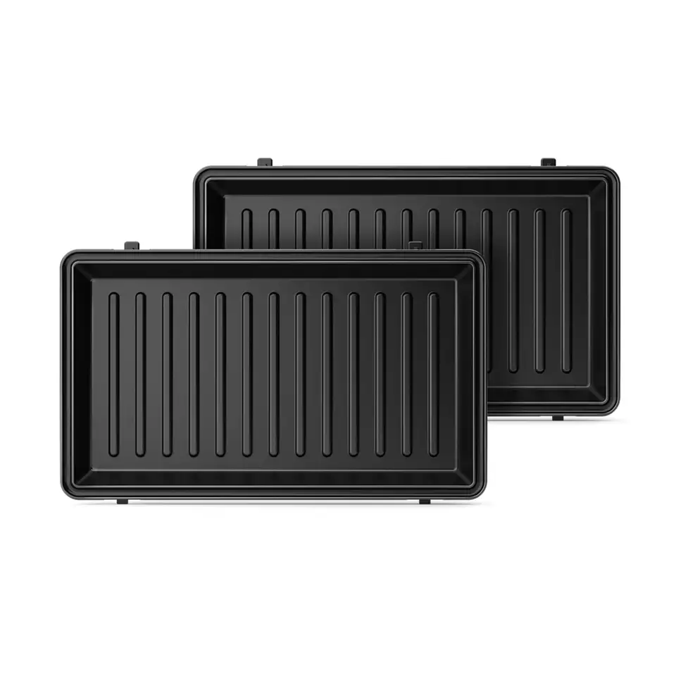 Zwei schwarze Backbleche mit Rillen, vor weißem Hintergrund, von oben betrachtet.