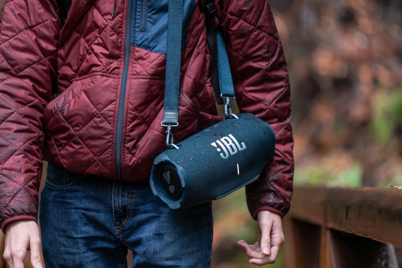 Ein Mann trägt einen JBL Bluetooth-Lautsprecher.