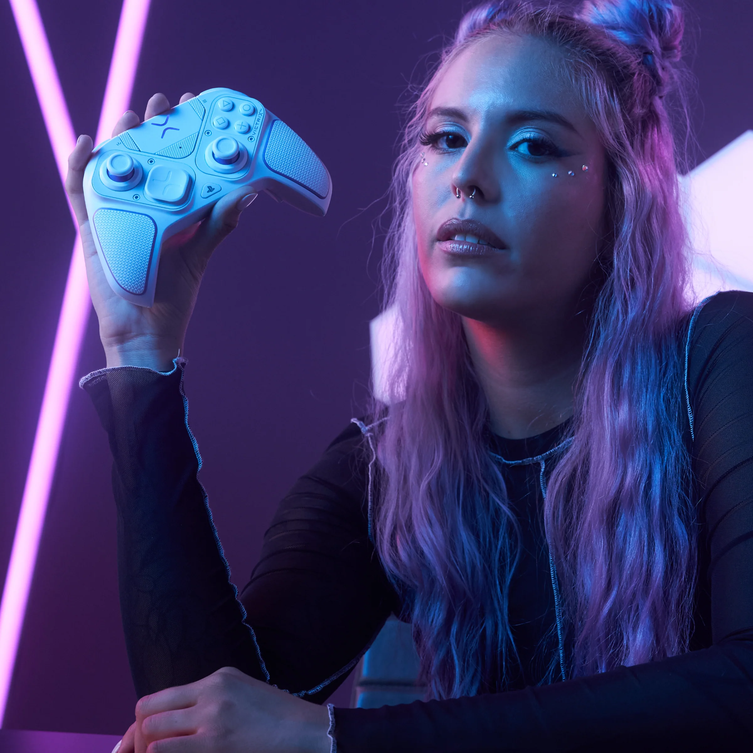 Giovane donna con i capelli viola che tiene in mano un controller di gioco bianco.