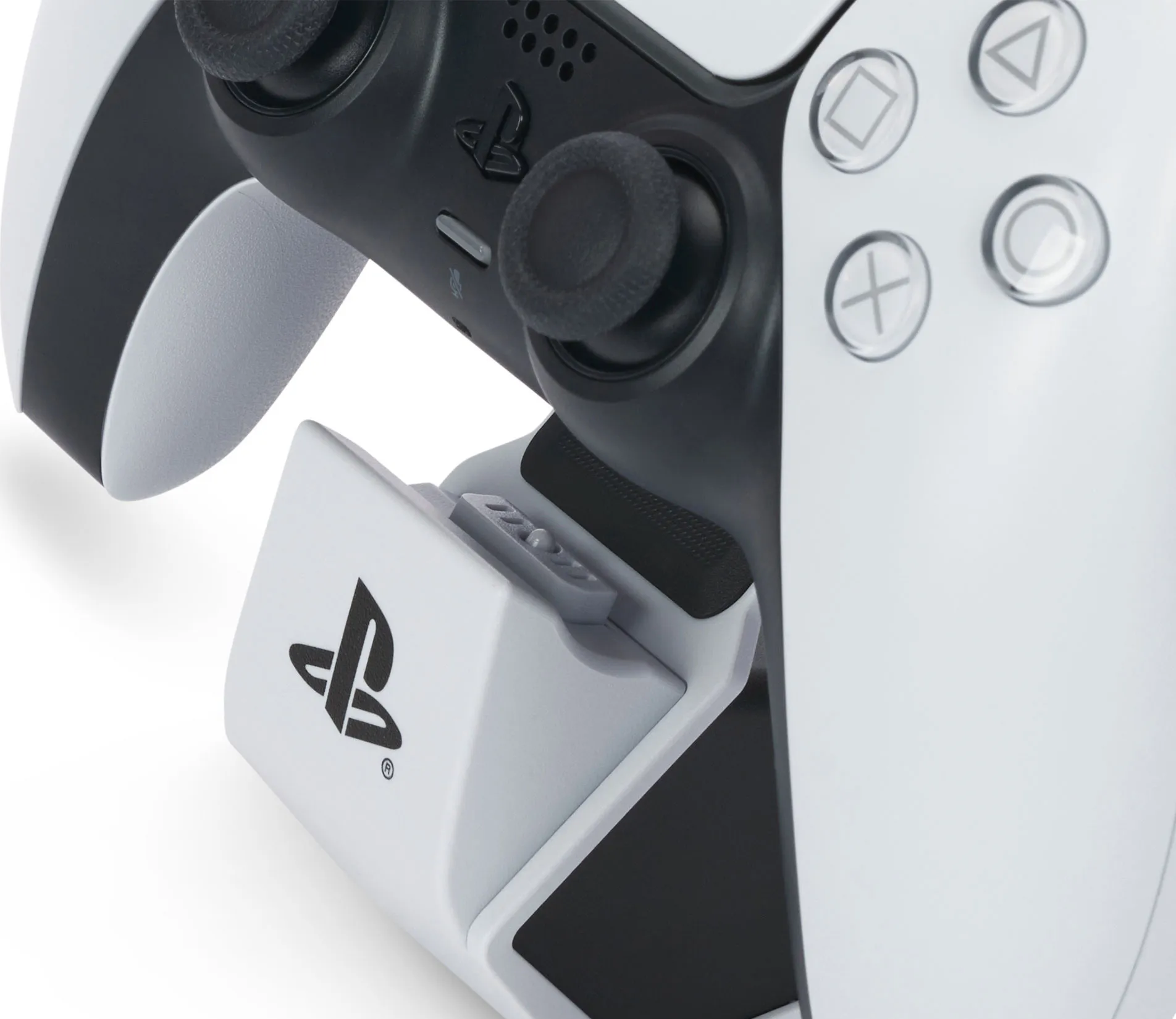 Gros plan d'une manette blanche PlayStation 5 sur un socle de chargement, avec le logo PlayStation visible.