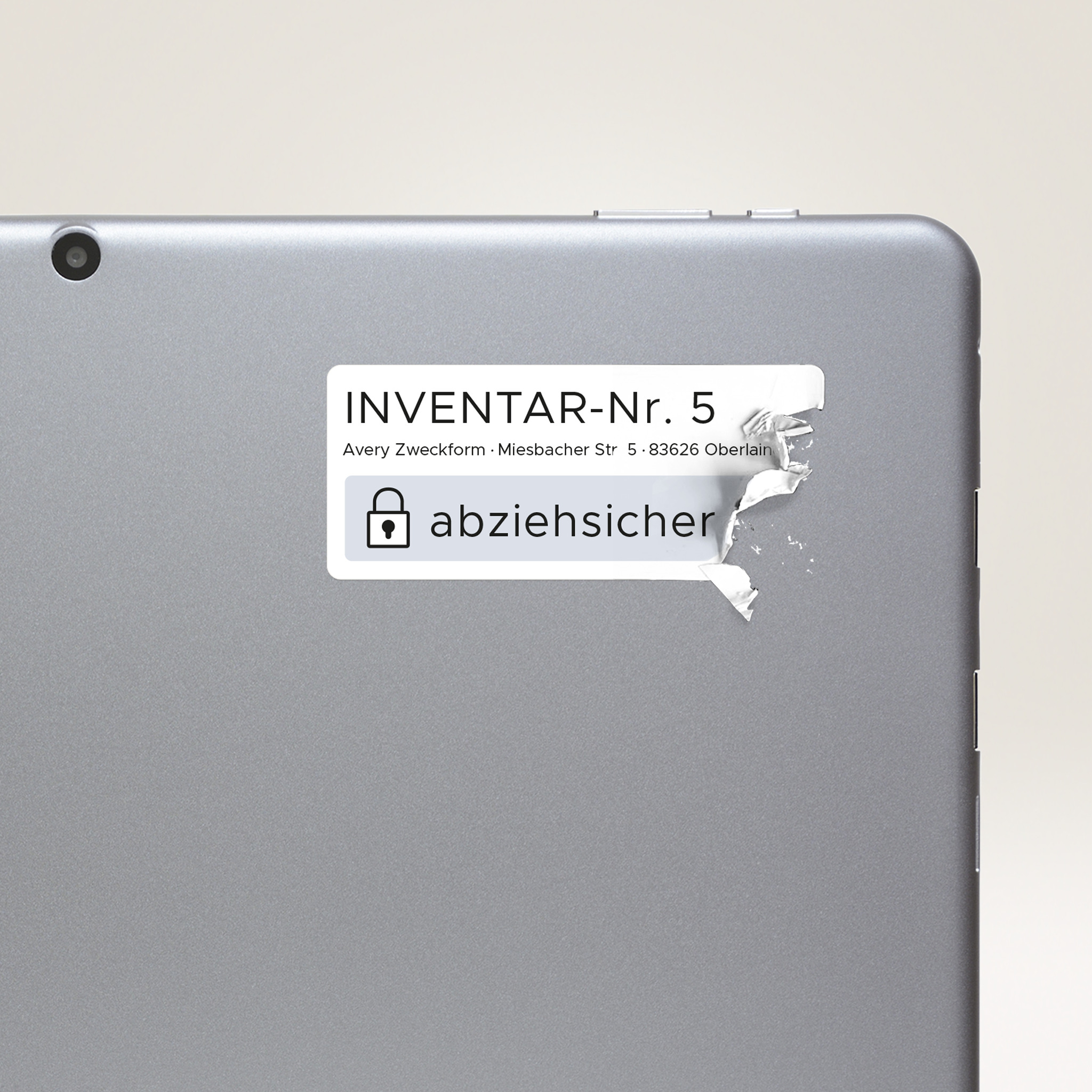 Ein Tablet mit einem teilweise abgezogenen Sicherheitsetikett. Der Aufkleber zeigt deutschen Text und ein Vorhängeschloss-Symbol.
