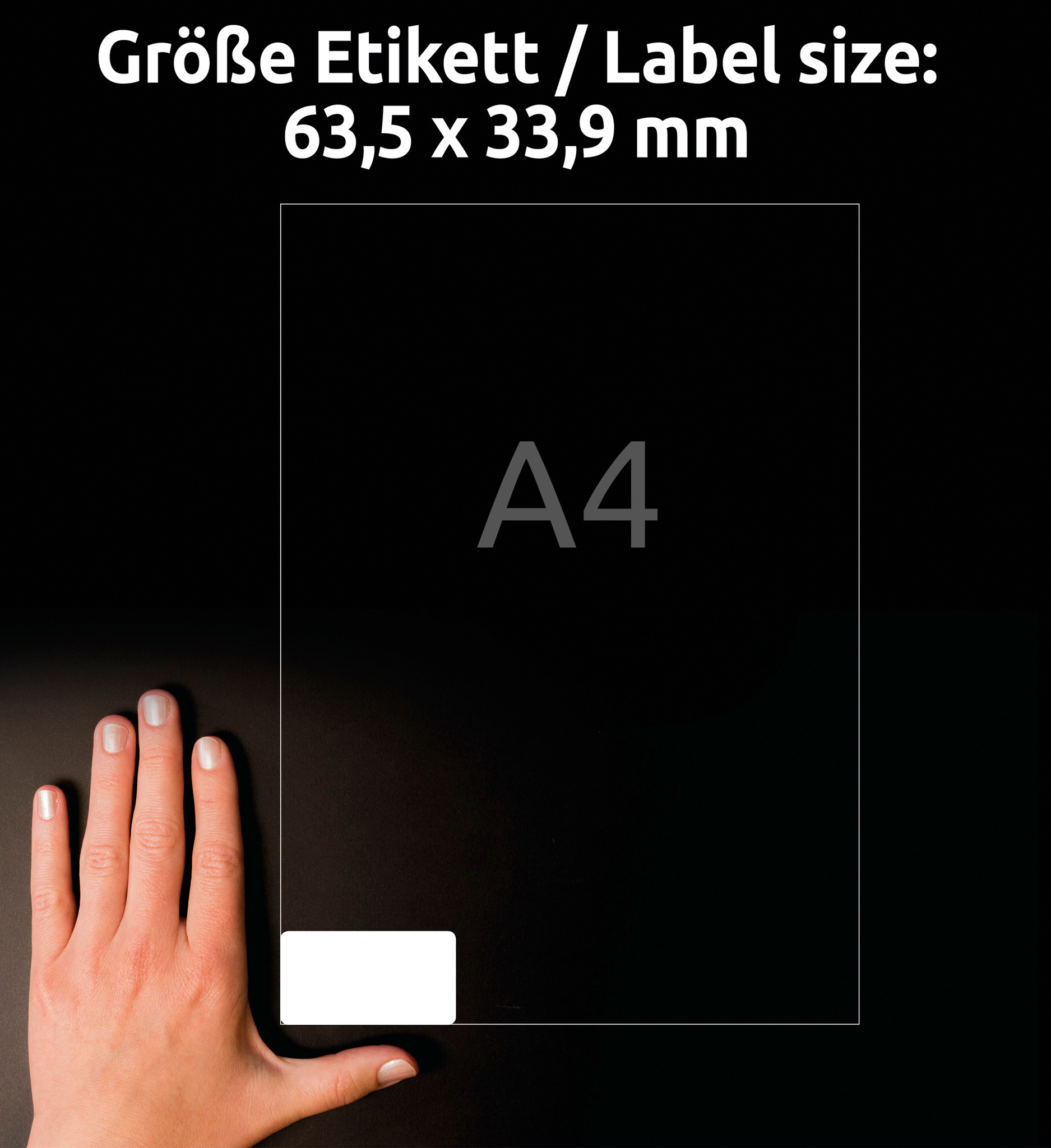 Hand auf schwarzer Oberfläche in der Nähe eines weißen Etiketts und eines Blattes. Text oben: Etikettengröße: 63,5 x 33,9 mm.