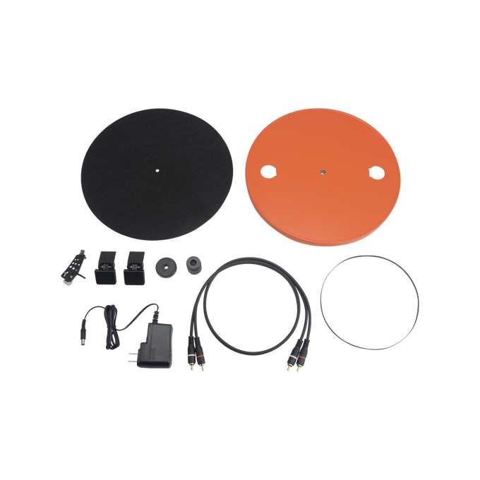 Componentes de un tocadiscos: plato, base, cables, correa, adaptador de corriente y piezas pequeñas, todo sobre fondo oscuro.
