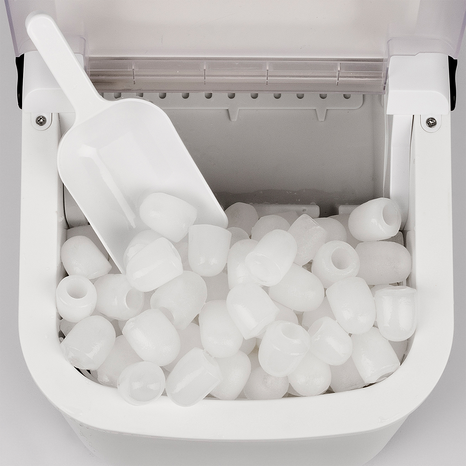 Macchina per il ghiaccio bianca con ghiaccio e un misurino all'interno, sfondo bianco.