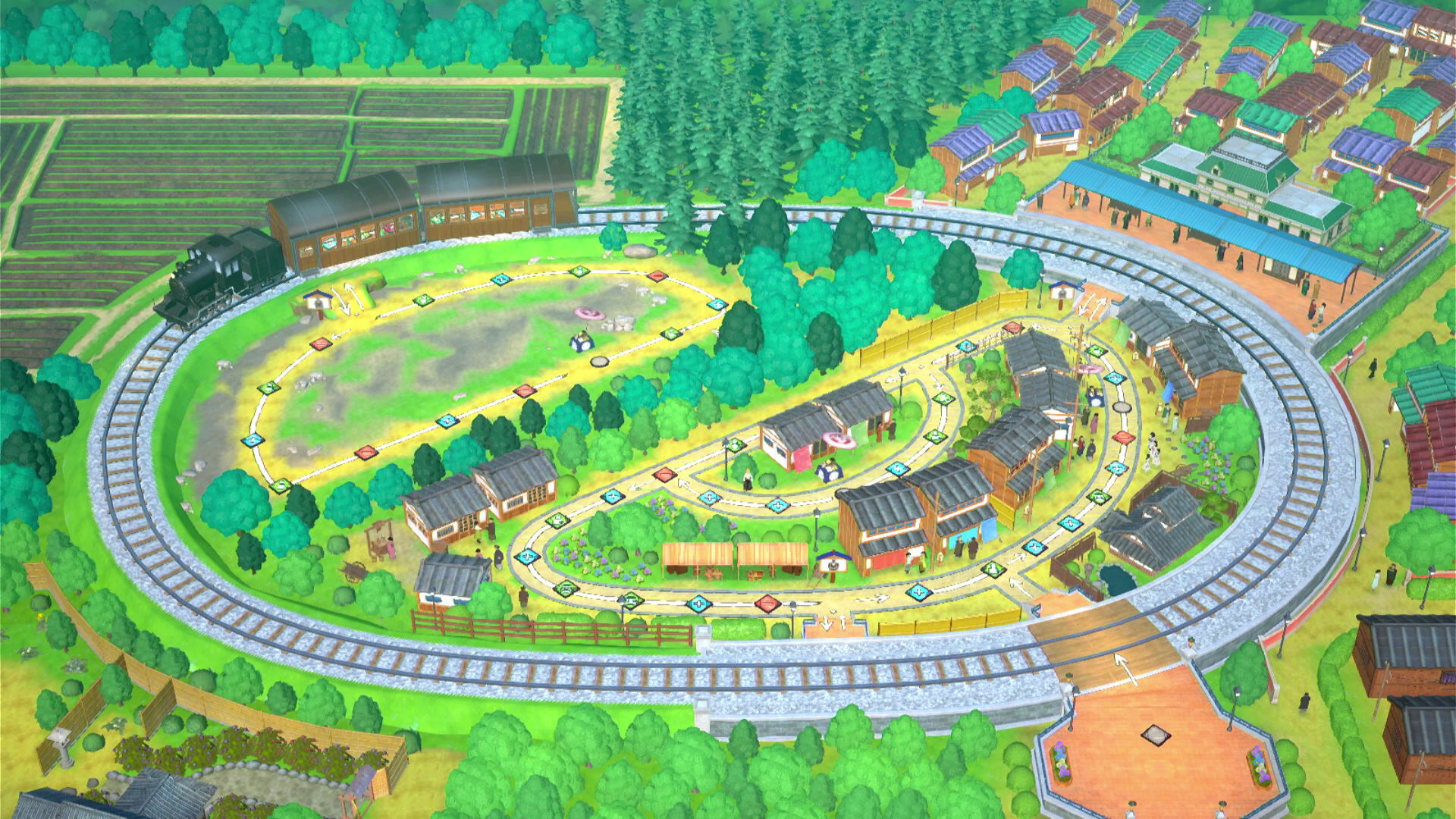 Vista dall'alto di un binario ferroviario attorno a un villaggio. Un treno è in alto a sinistra.