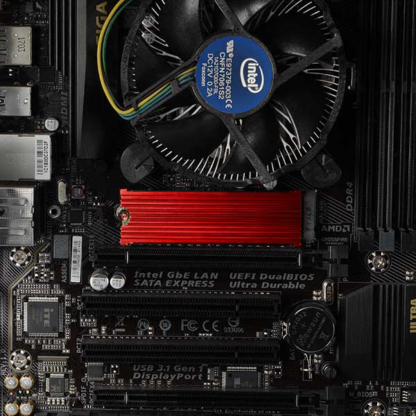 Közelkép egy számítógép alaplapról, CPU ventilátorral, piros hűtőbordával, alkatrészekkel.