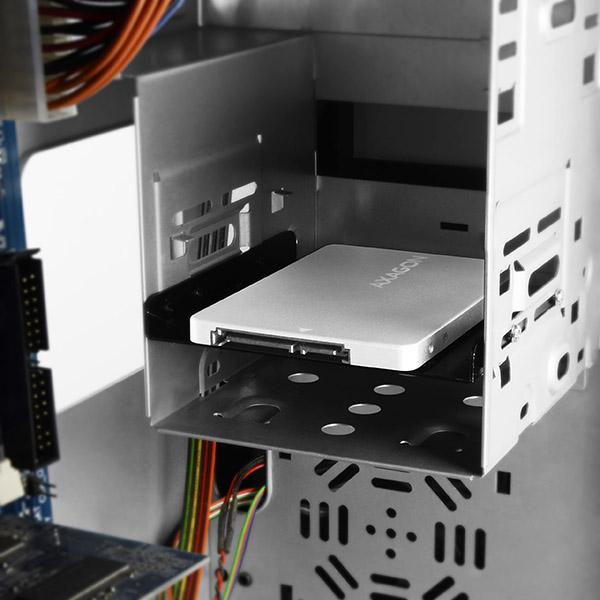 Egy számítógépház, egy SSD-vel beépítve egy rekeszbe, kábelekkel és egyéb alkatrészekkel.