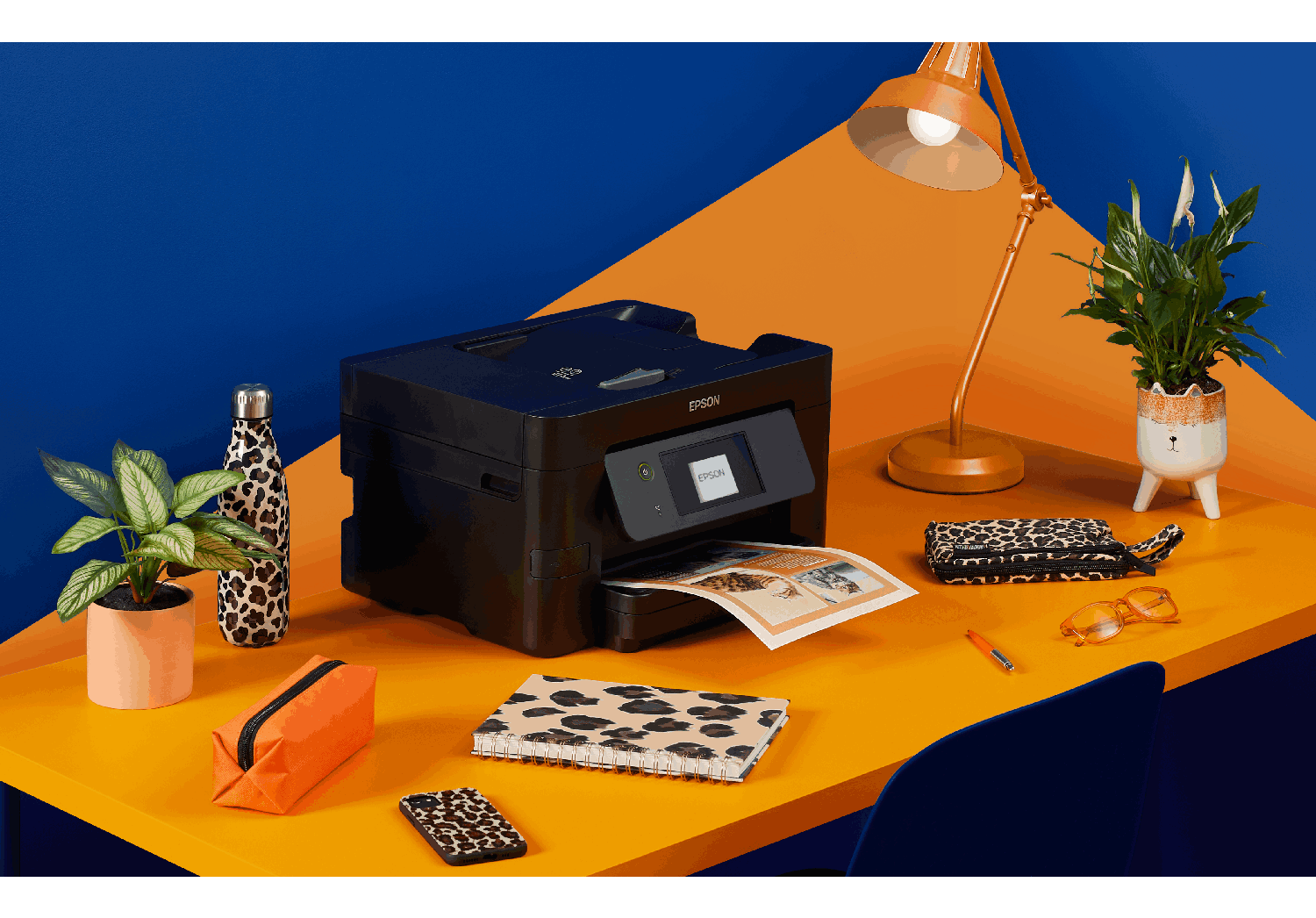 Una impresora en un escritorio con accesorios de estampado de leopardo.