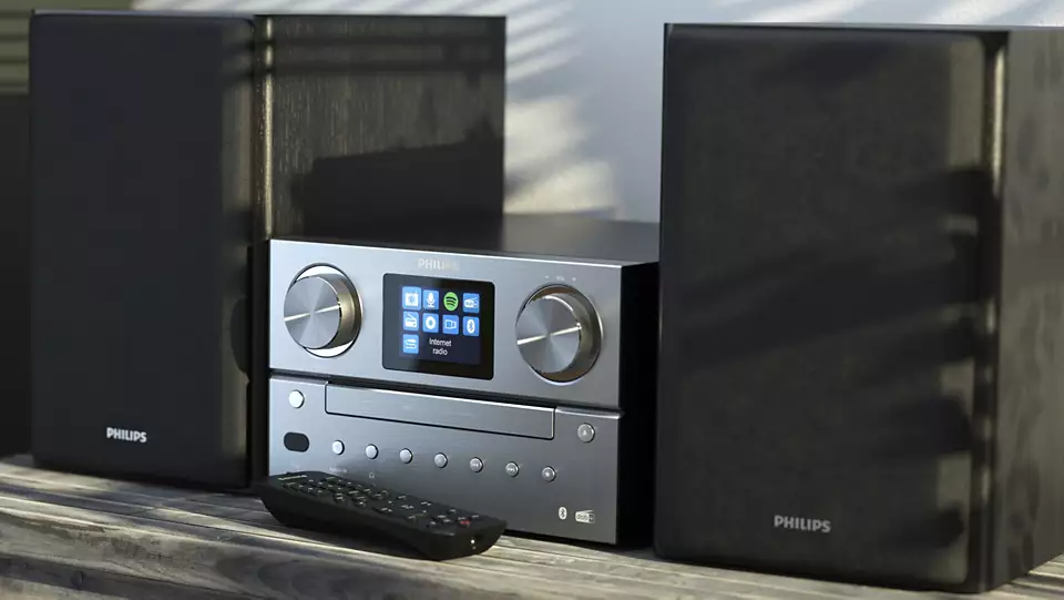 Un moderno sistema stereo con altoparlanti, telecomando e display. Appoggiato su una superficie di legno.