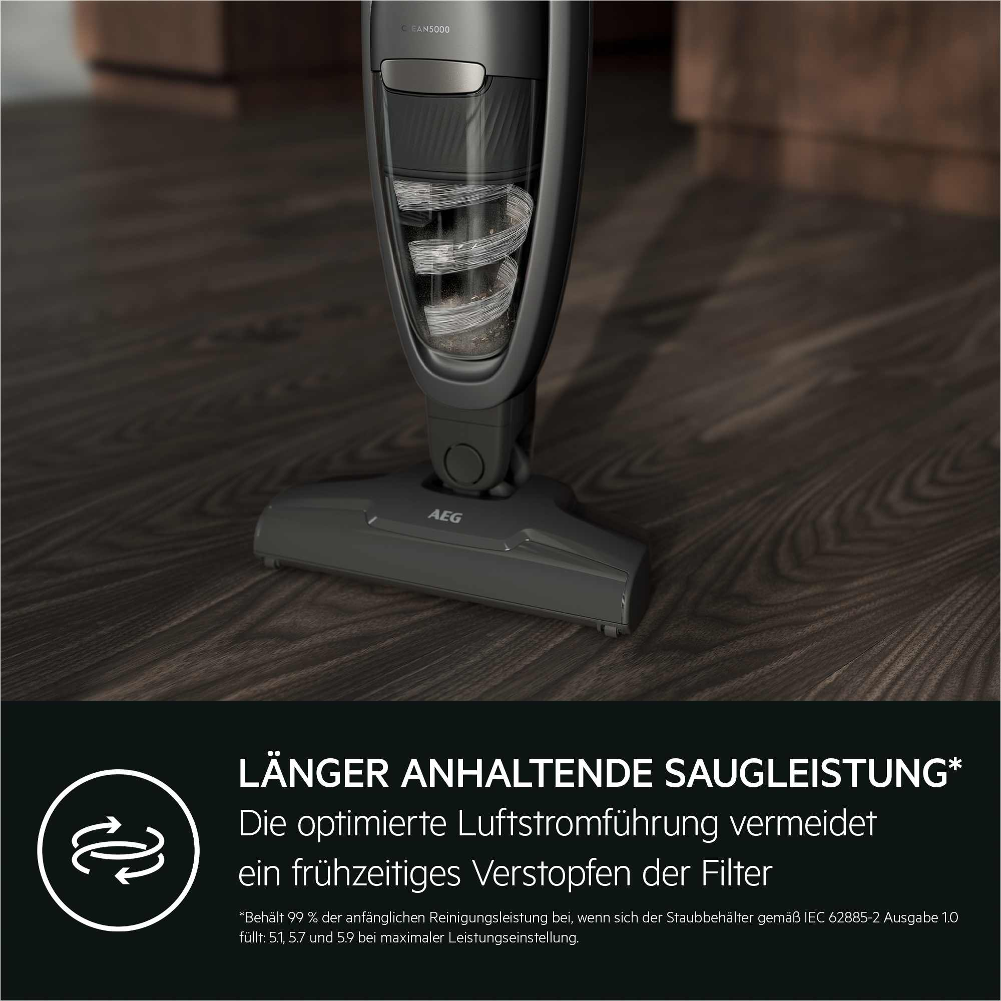 Dunkelgrauer Staubsauger auf Holzboden. Der Text lautet 'LÄNGER ANHALTENDE SAUGLEISTUNG'.