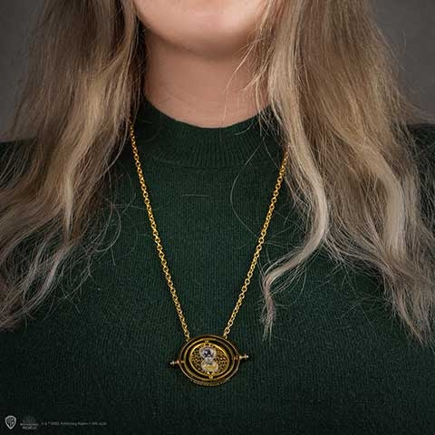 Eine Frau mit blonden Haaren trägt einen grünen Pullover mit einer goldenen Halskette.