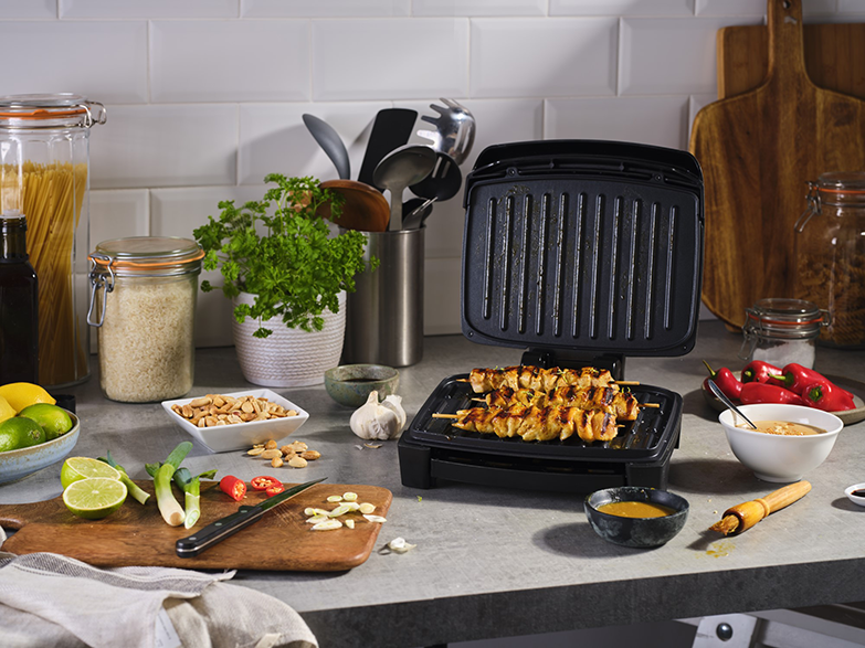 Konyhai jelenet ételkészítéssel. Grill nyársakkal, zöldségekkel és szószokkal a pulton.