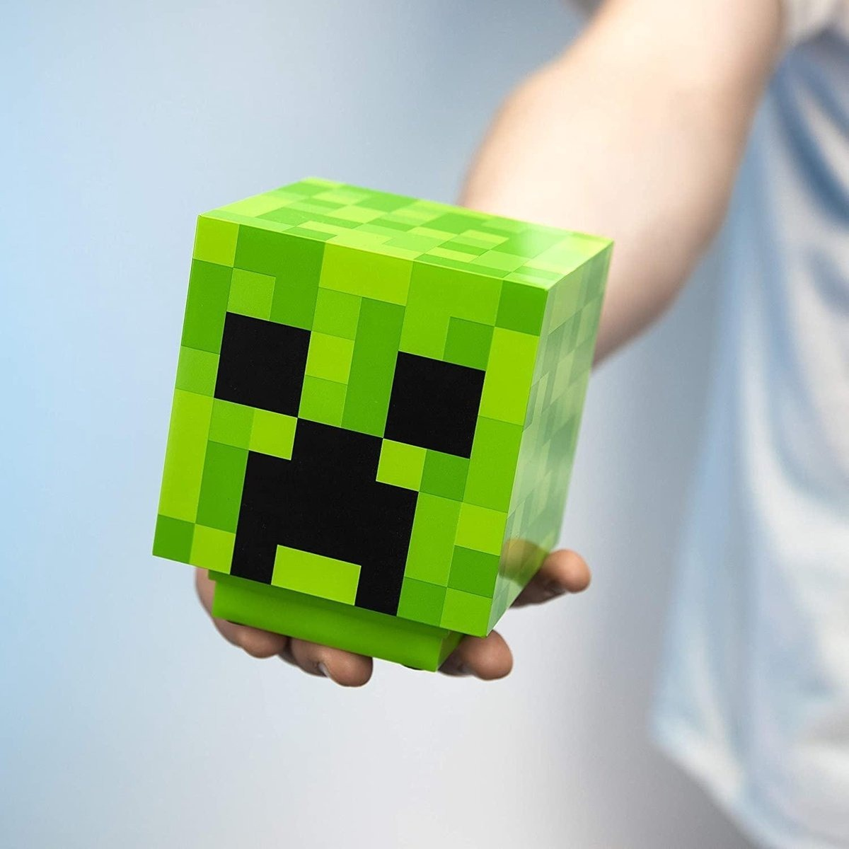 Green pixelated Minecraft Creeper head toy, held by a hand.