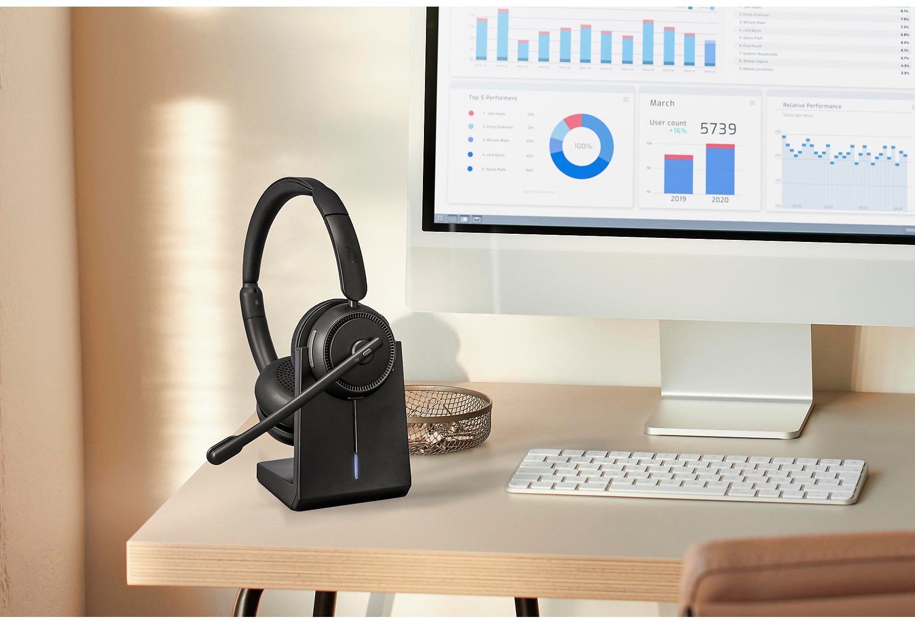Schwarzes Headset auf einem Ständer mit Tastatur und Monitor, der Daten anzeigt.