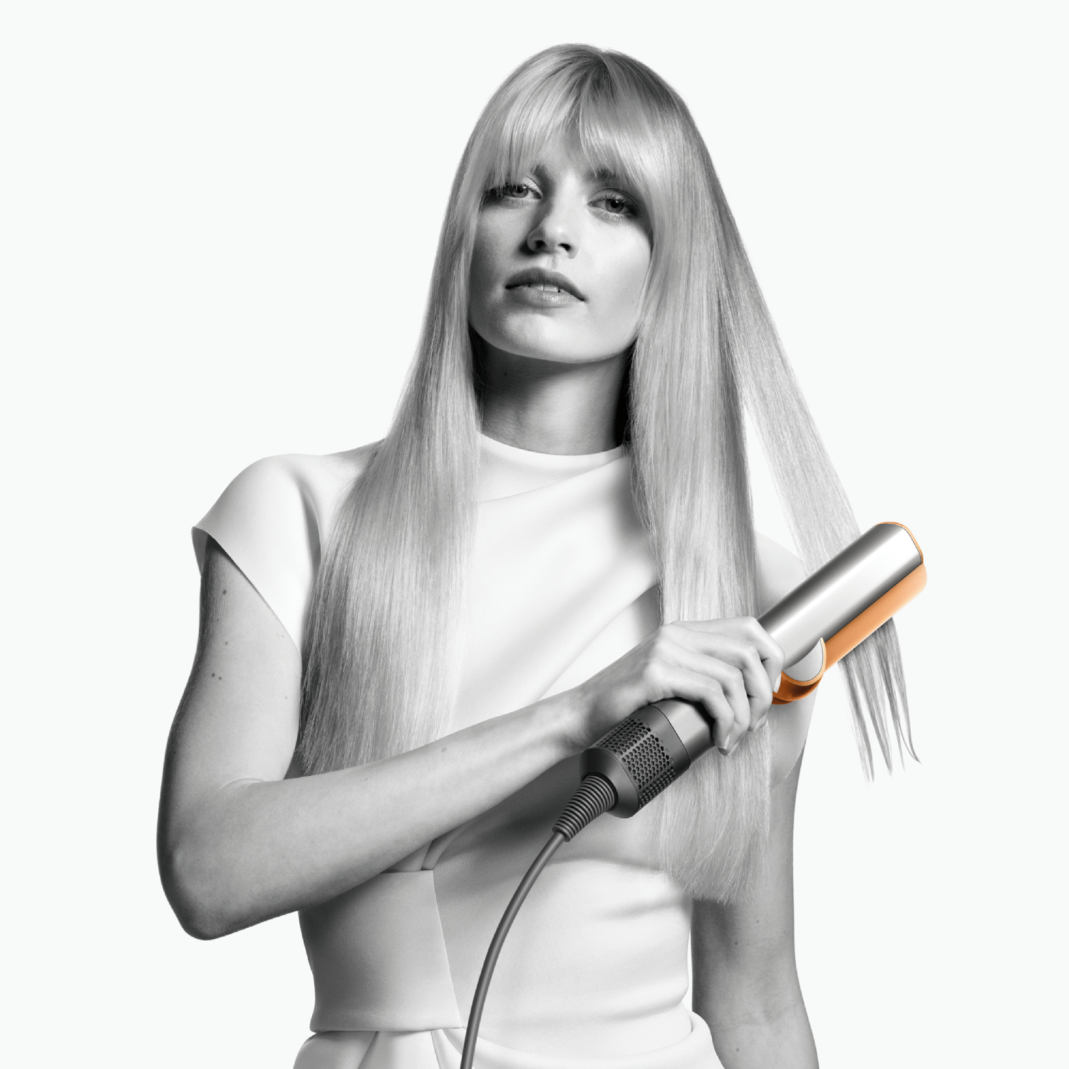 Mujer peinando su largo cabello rubio con una plancha de pelo.