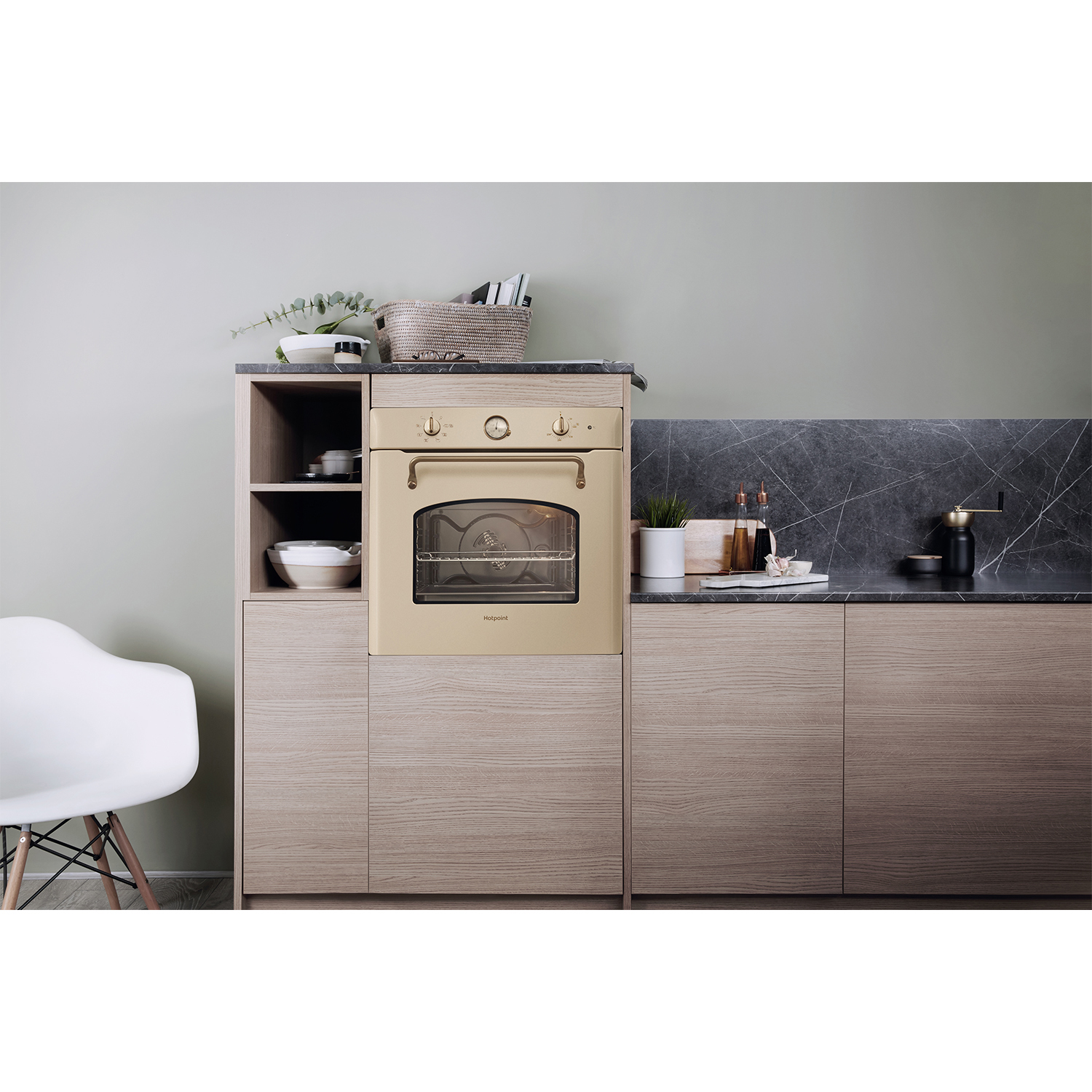 Forno beige in un mobile di legno. Sedia bianca, piano di lavoro sono visibili.