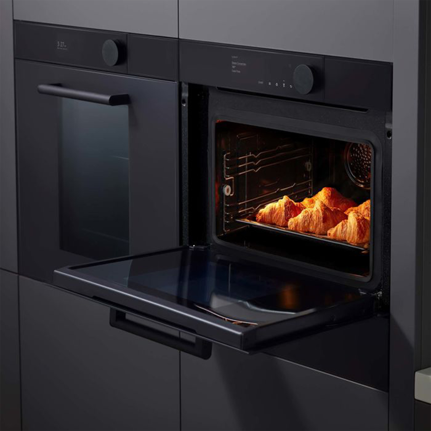 Forno nero con la porta aperta e croissant sulla griglia.