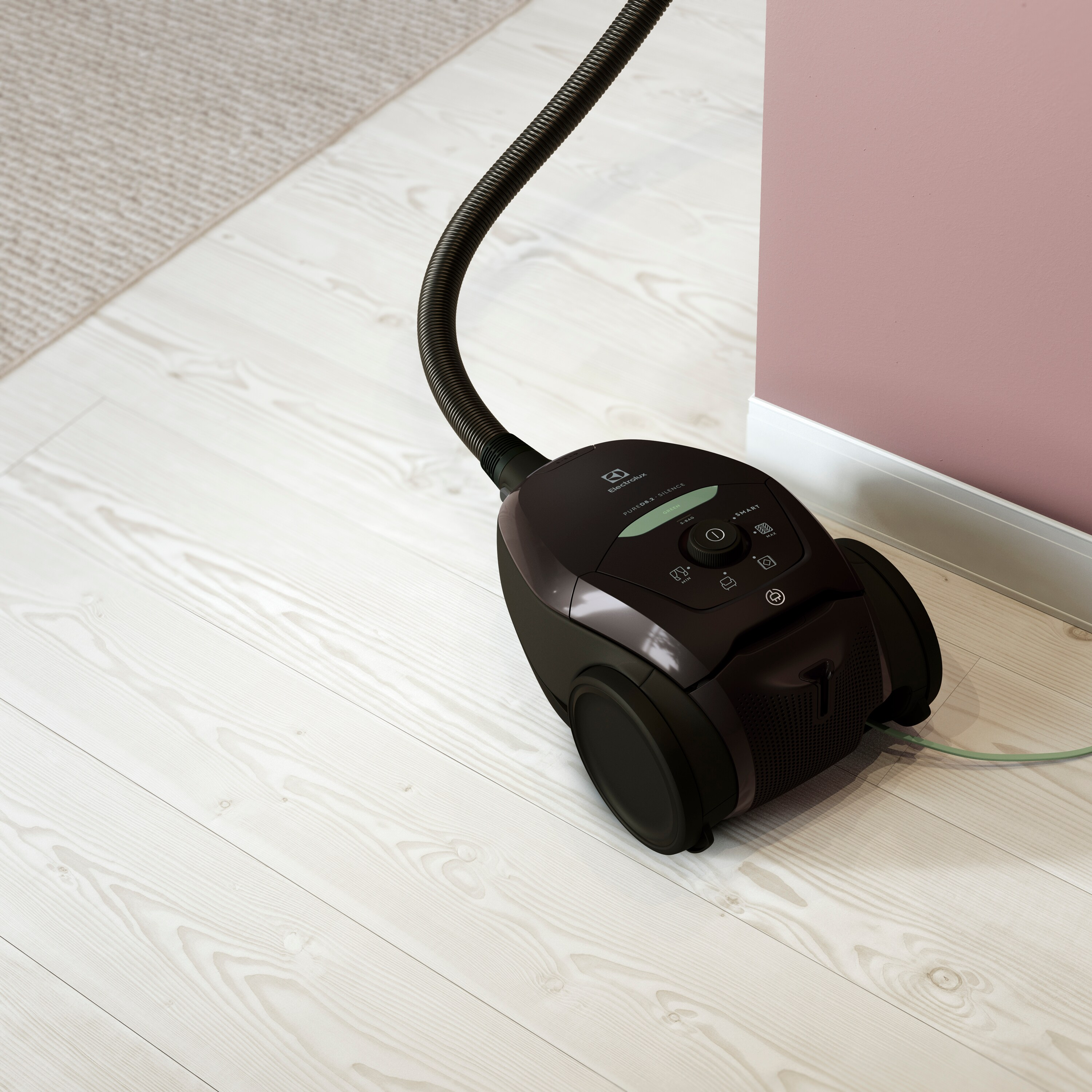 Aspirateur sur un plancher en bois à côté d'un mur rose.