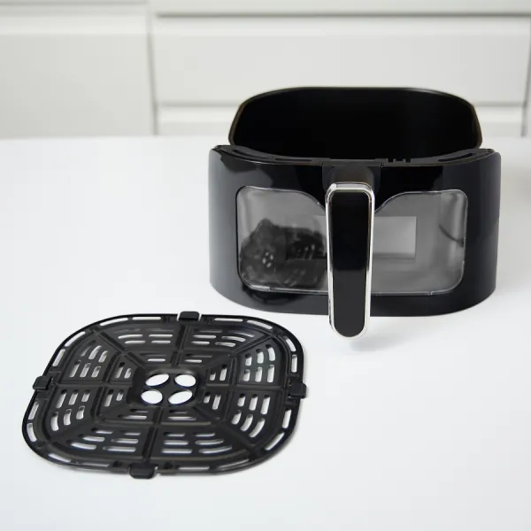 Czarna frytkownica beztłuszczowa, czarny grill i biały stół. Pokrywa jest zdjęta.