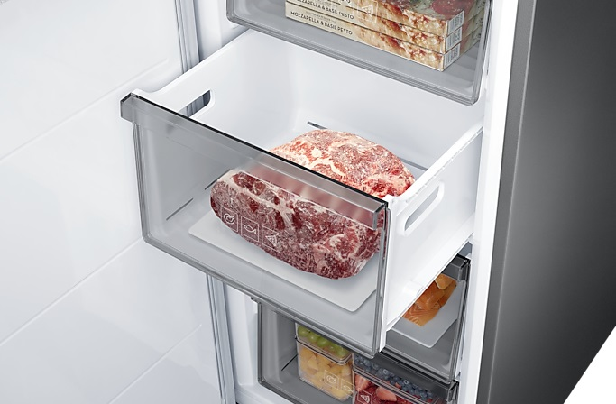 Wnętrze lodówki z zamrożonym mięsem w szufladzie, widoczne przegrody.