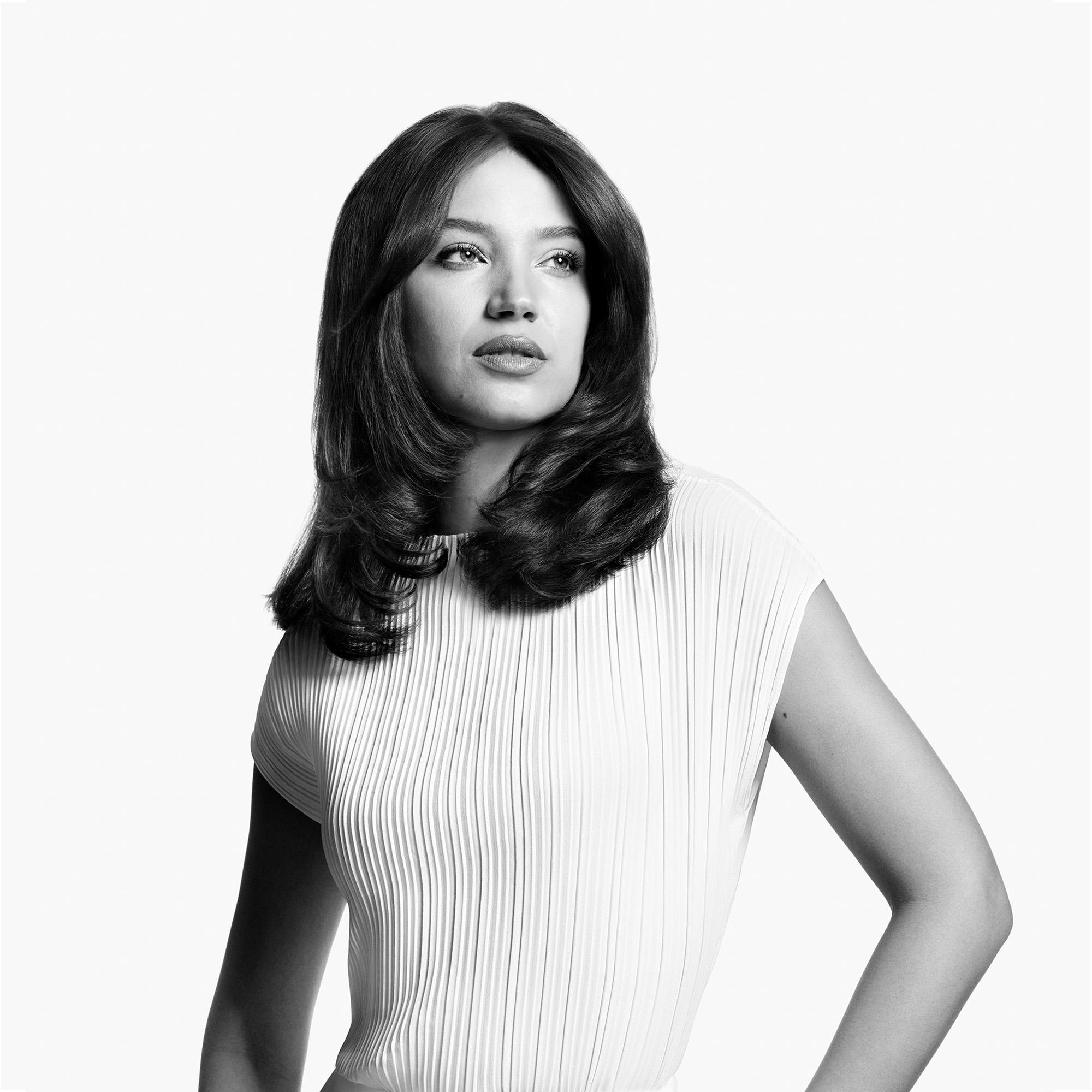 Eine Frau in einem weißen Oberteil, die nach rechts schaut.