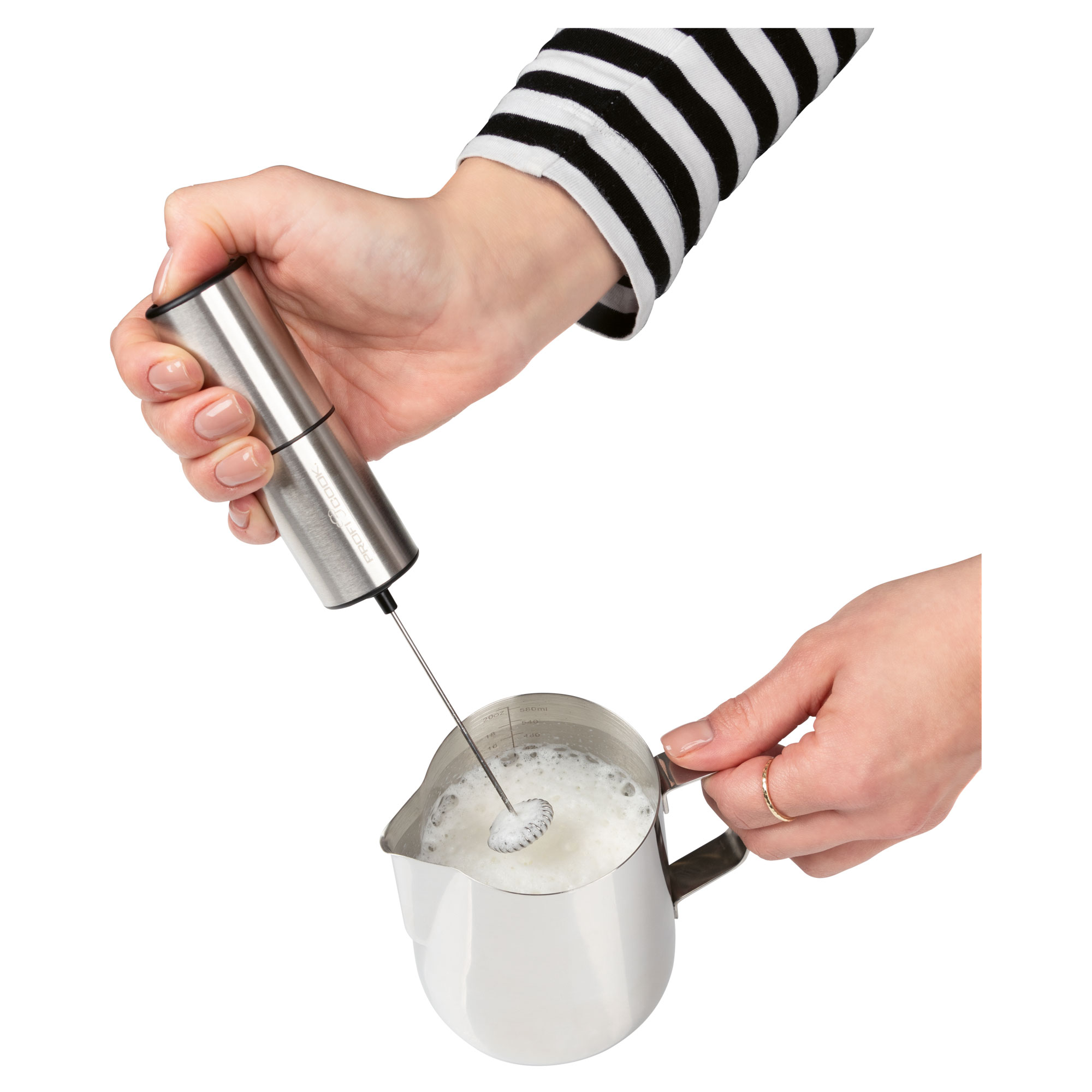 Person hält silbernen Milchaufschäumer über einem Metallkrug mit Milch.
