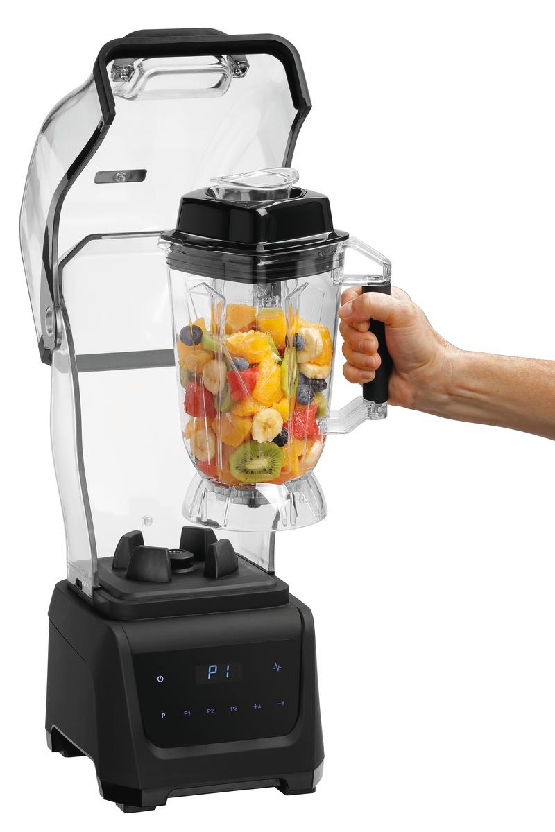 Ein Mixer mit Früchten im Inneren. Eine Hand hält den Griff. Der Mixer ist schwarz und transparent. Früchte sind Kiwi, Orangen und Beeren.