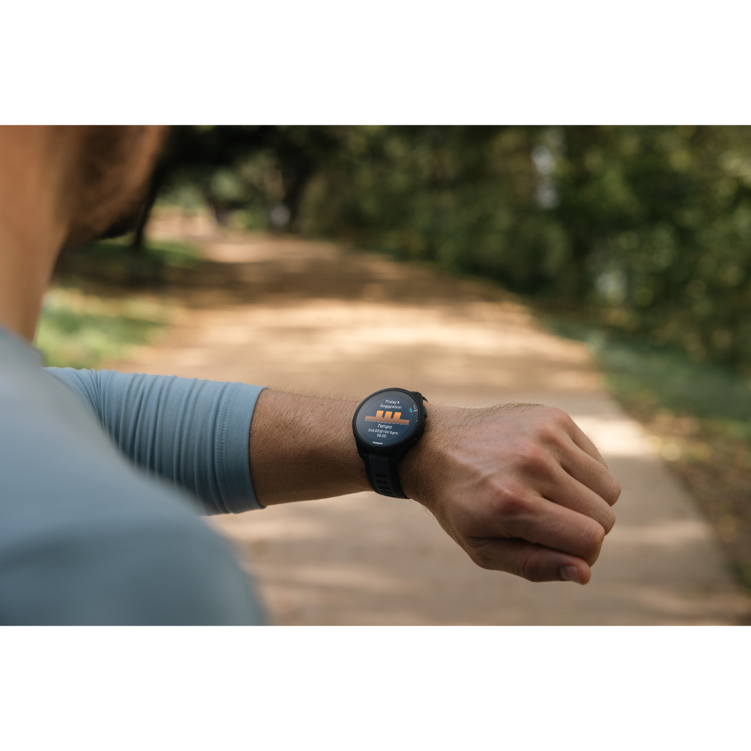 Man with watch running on path. Trees in the background.