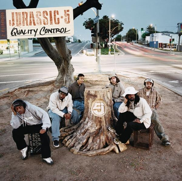 Albumcover mit sechs Männern vor einem Baumstumpf, mit einem Schild mit der Aufschrift 'Jurassic 5'.