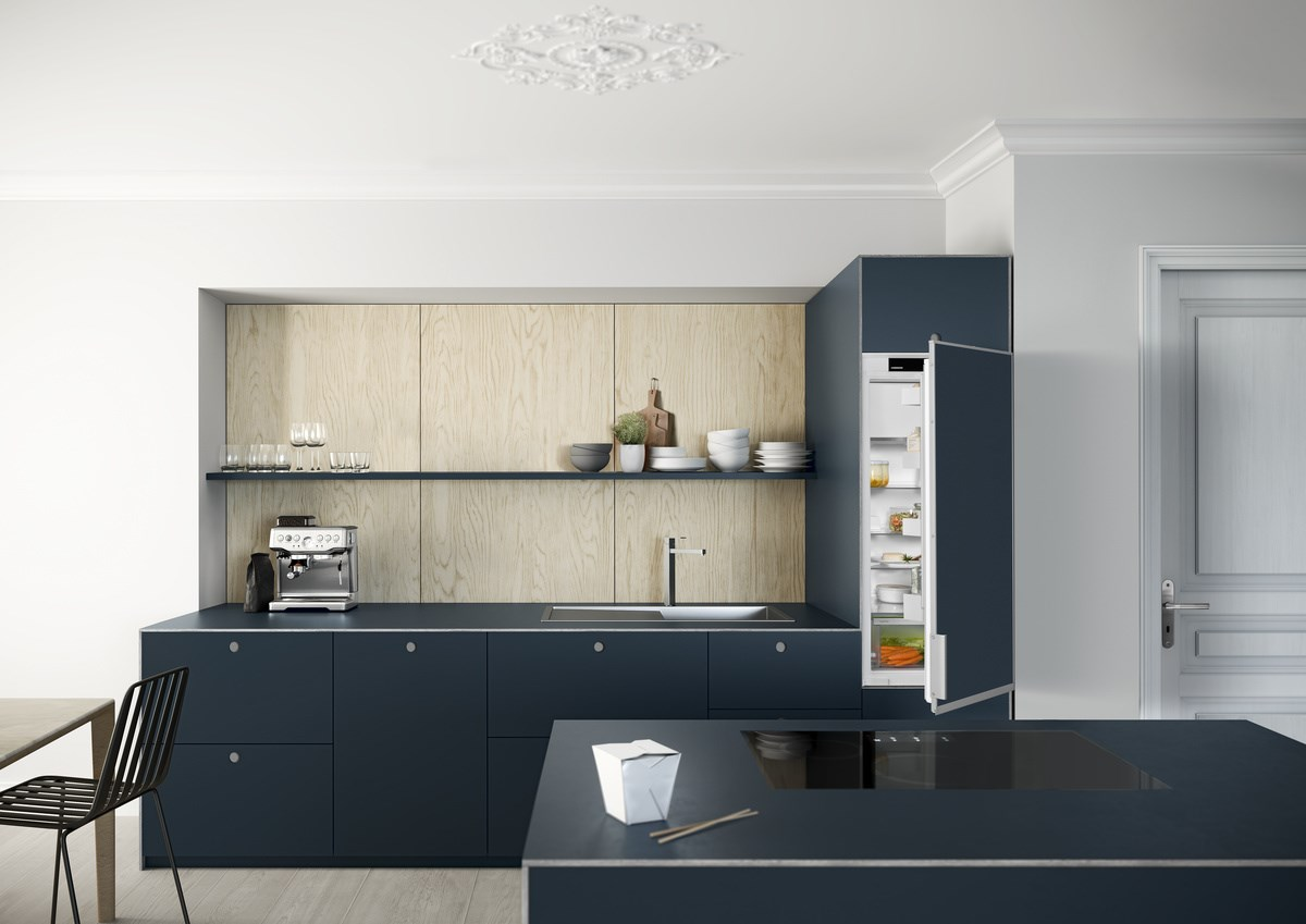 Eine moderne Küche mit blauen Schränken, einem Holzakzent und einem offenen Kühlschrank.