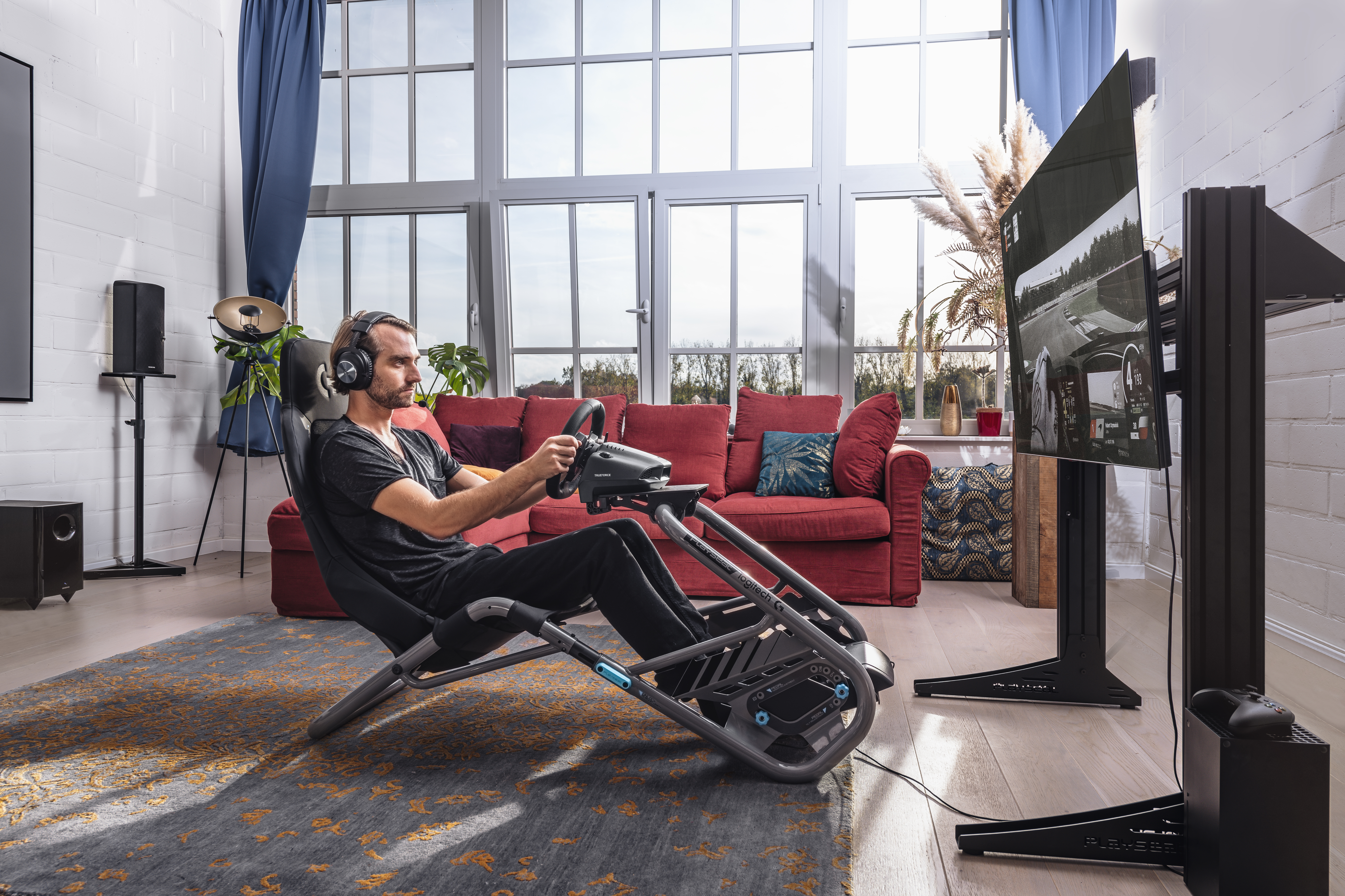 Un homme est dans une chaise de jeu avec un volant regardant la télévision.