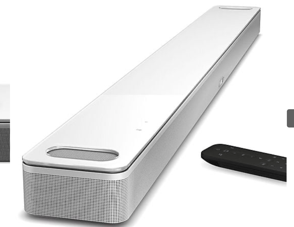 Eine lange weiße Soundbar mit einer schwarzen Fernbedienung auf weißer Oberfläche.