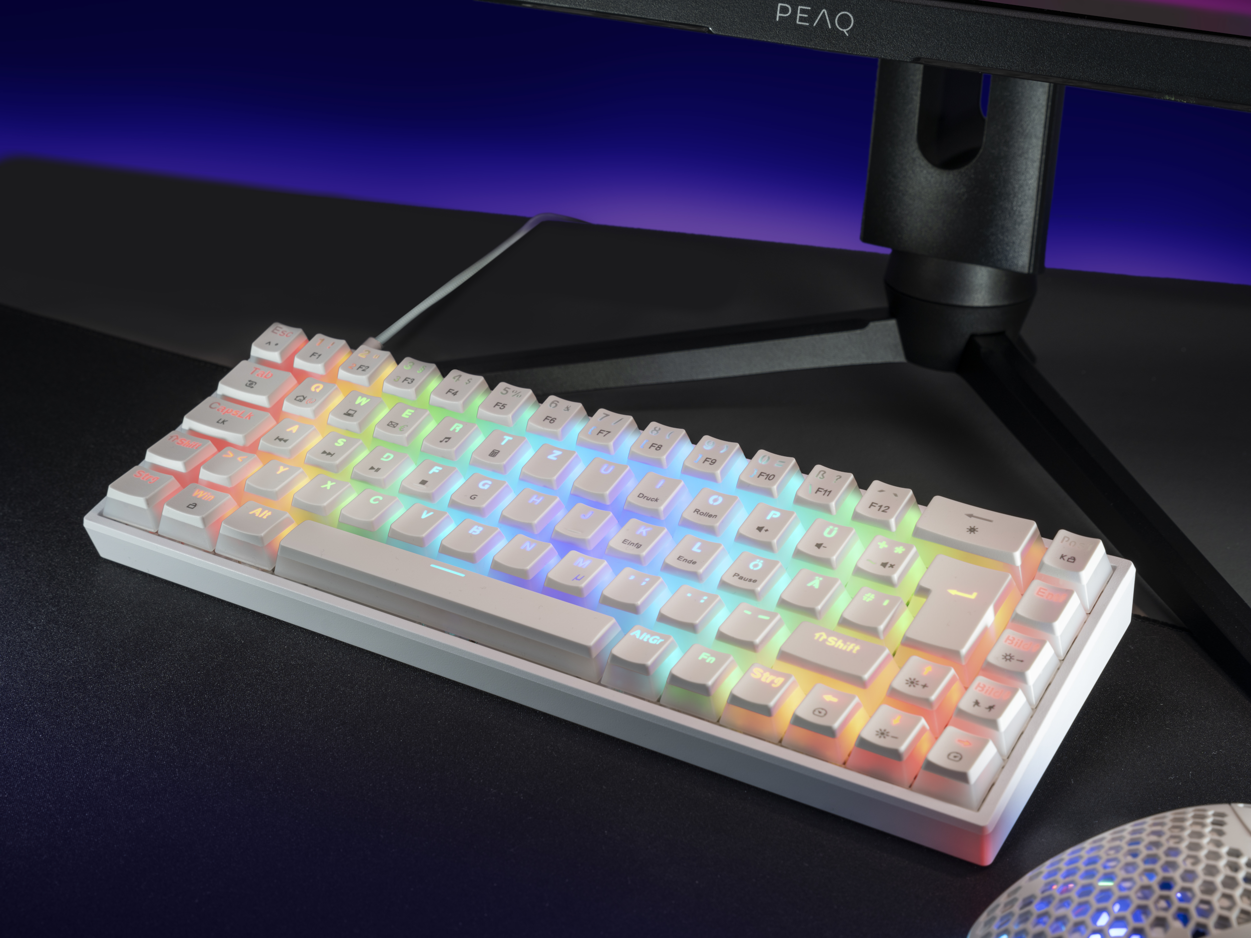 Eine weiße mechanische Tastatur mit farbenfroher Tastenbeleuchtung und einem schwarzen Schreibtisch.