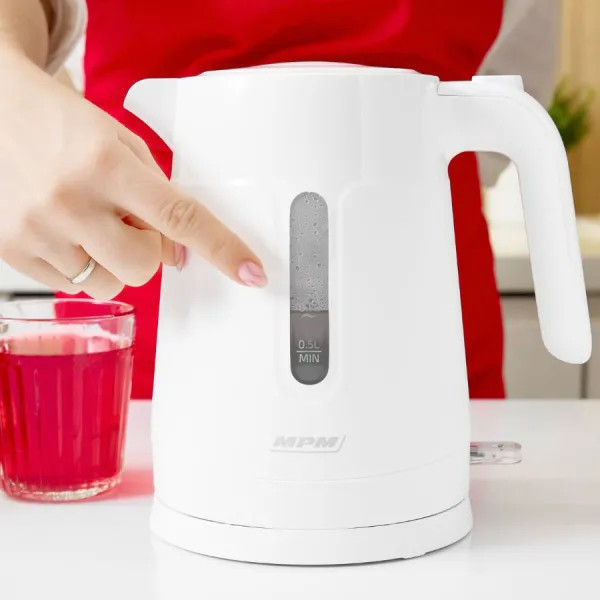 Biały czajnik elektryczny, osoba dotyka wskaźnika poziomu wody.