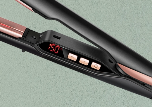 Zbliżenie na panel sterowania czarnej i różowo-złotej prostownicy do włosów.