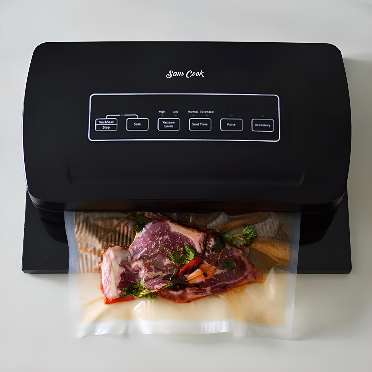 Czarna zgrzewarka próżniowa marki Sam Cook. Stek z ziołami w plastikowej torbie, gotowy do zgrzania.