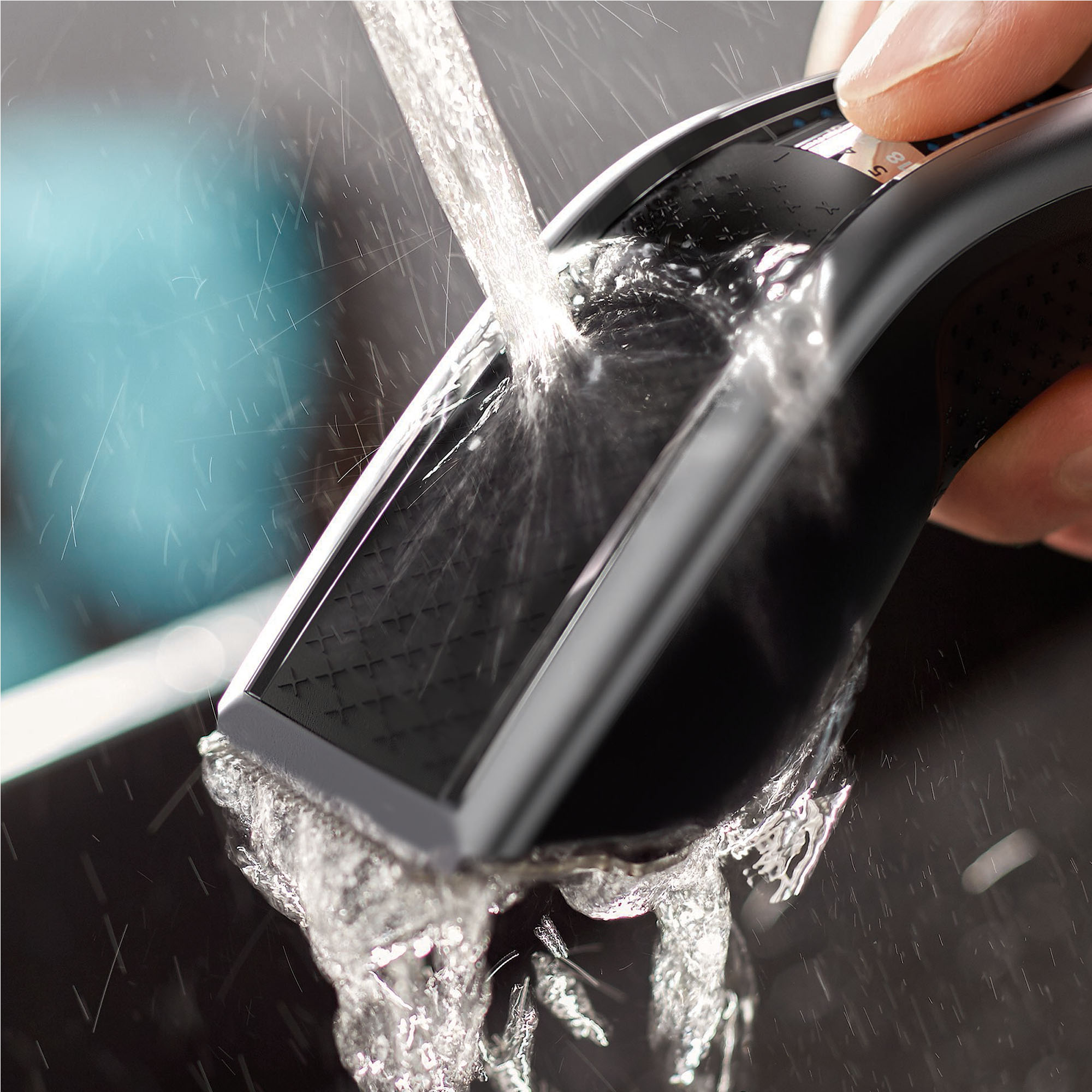 Czarna maszynka do strzyżenia włosów płukana wodą. Woda spływa po ostrzach.