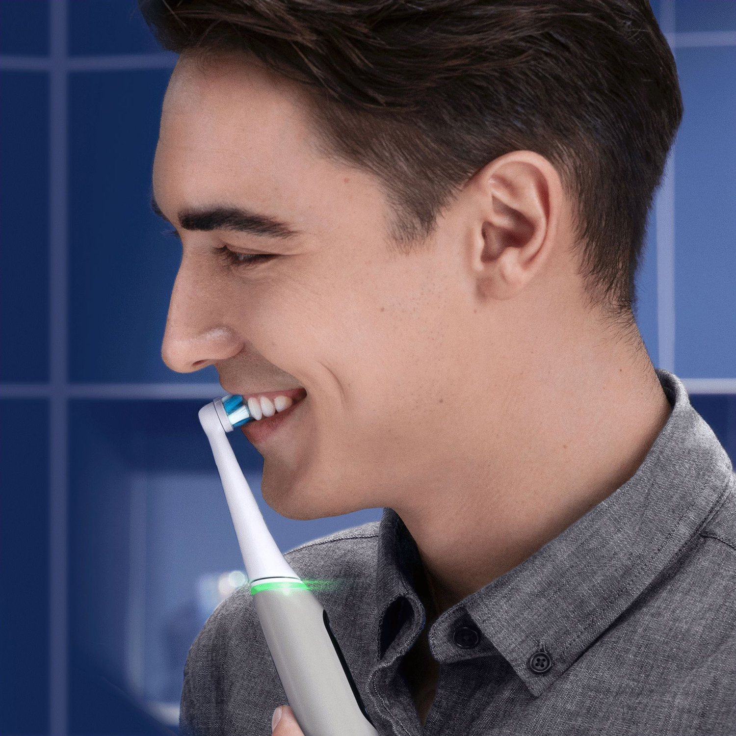 Un uomo che si lava i denti con uno spazzolino elettrico. Lo spazzolino ha una luce verde.