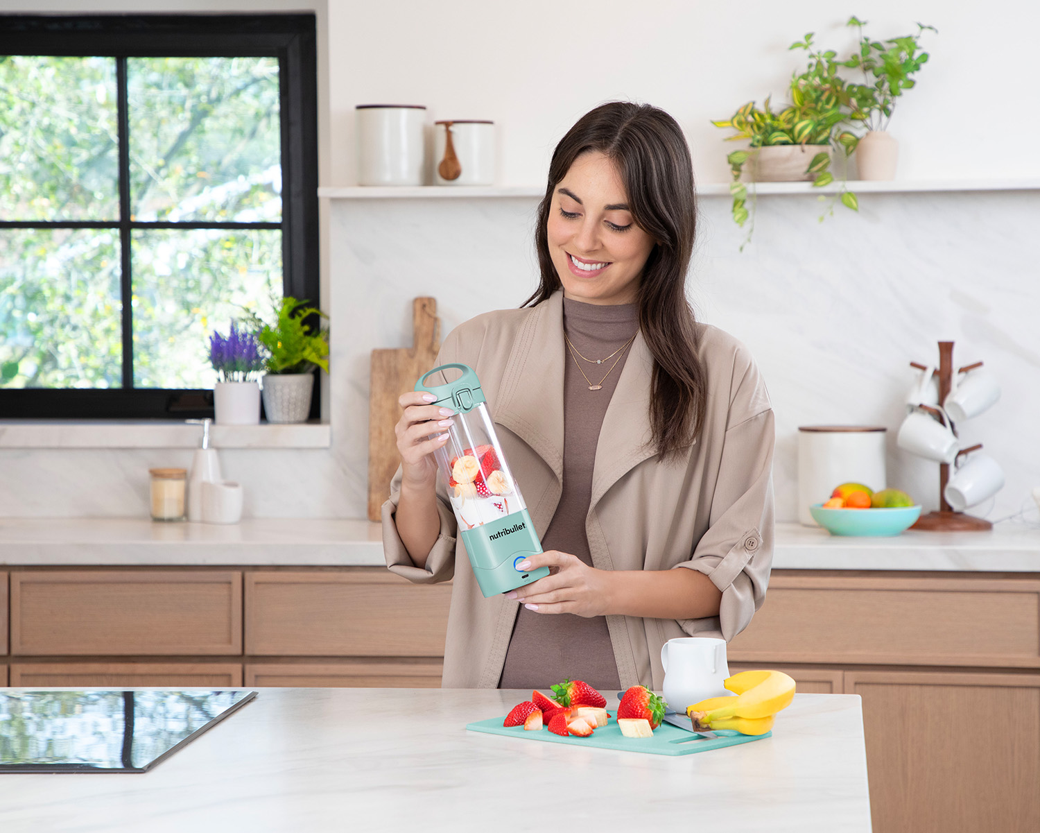 Frau mit Mixer, Früchten und Küchenhintergrund.