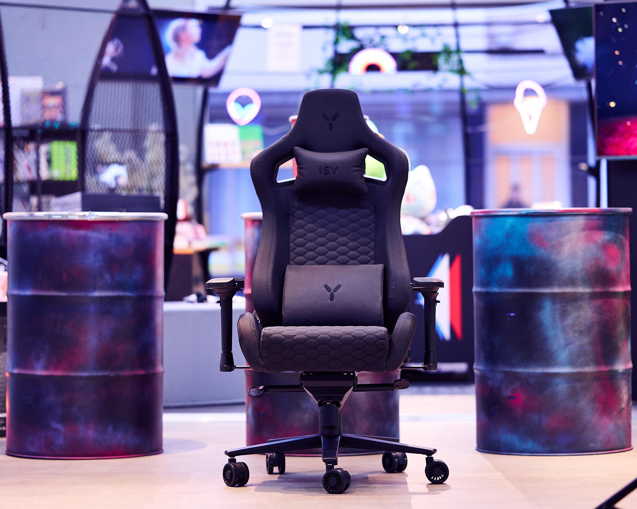 Schwarzer Gaming-Stuhl in einem Raum mit Fässern und Neonlichtern.
