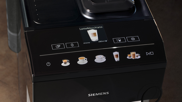 Bir latte macchiato ve simgeler gösteren bir kahve makinesi ekranının yakın çekimi.