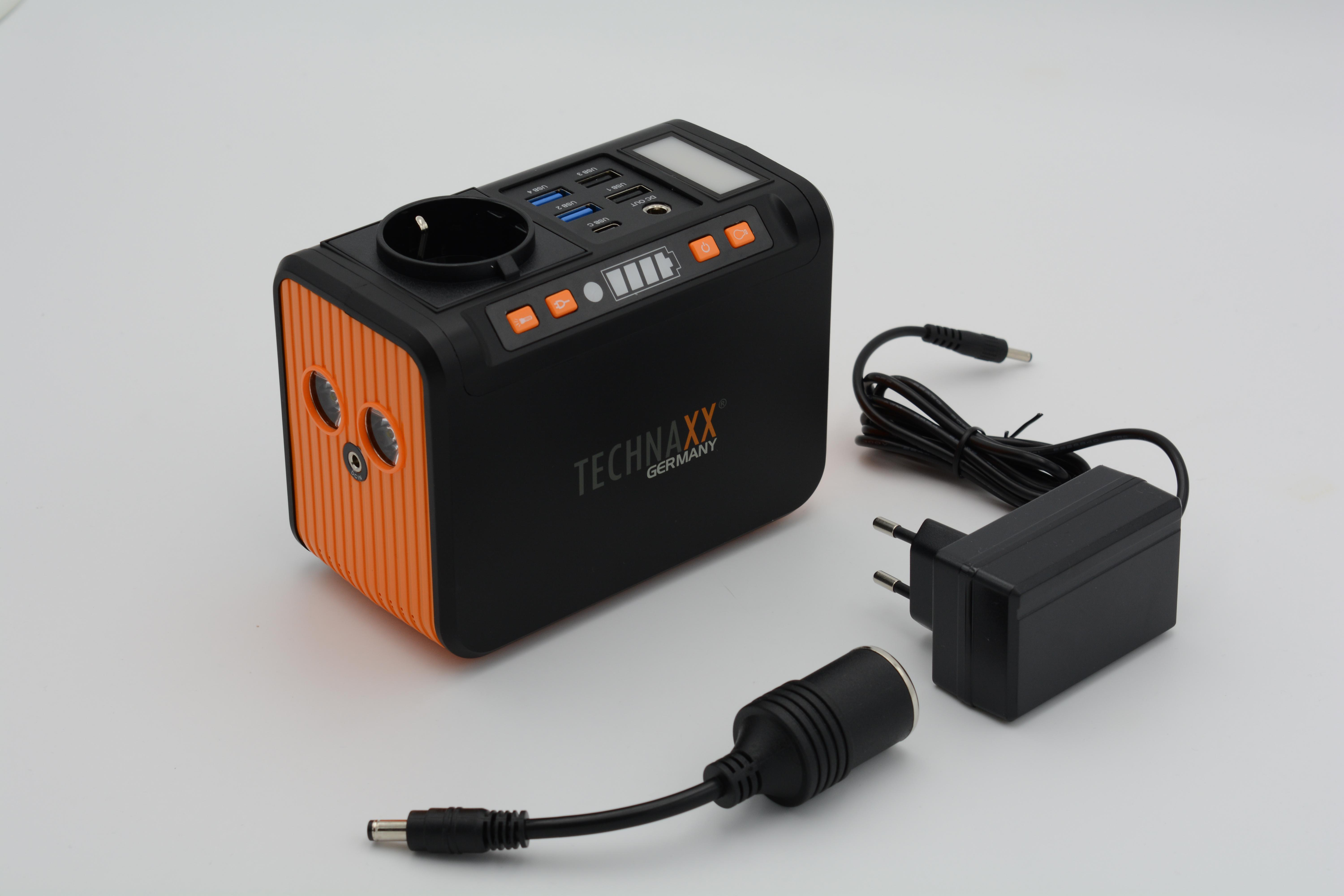 Schwarze und orangefarbene Powerstation mit mehreren Anschlüssen, Ladekabel und Adapter.