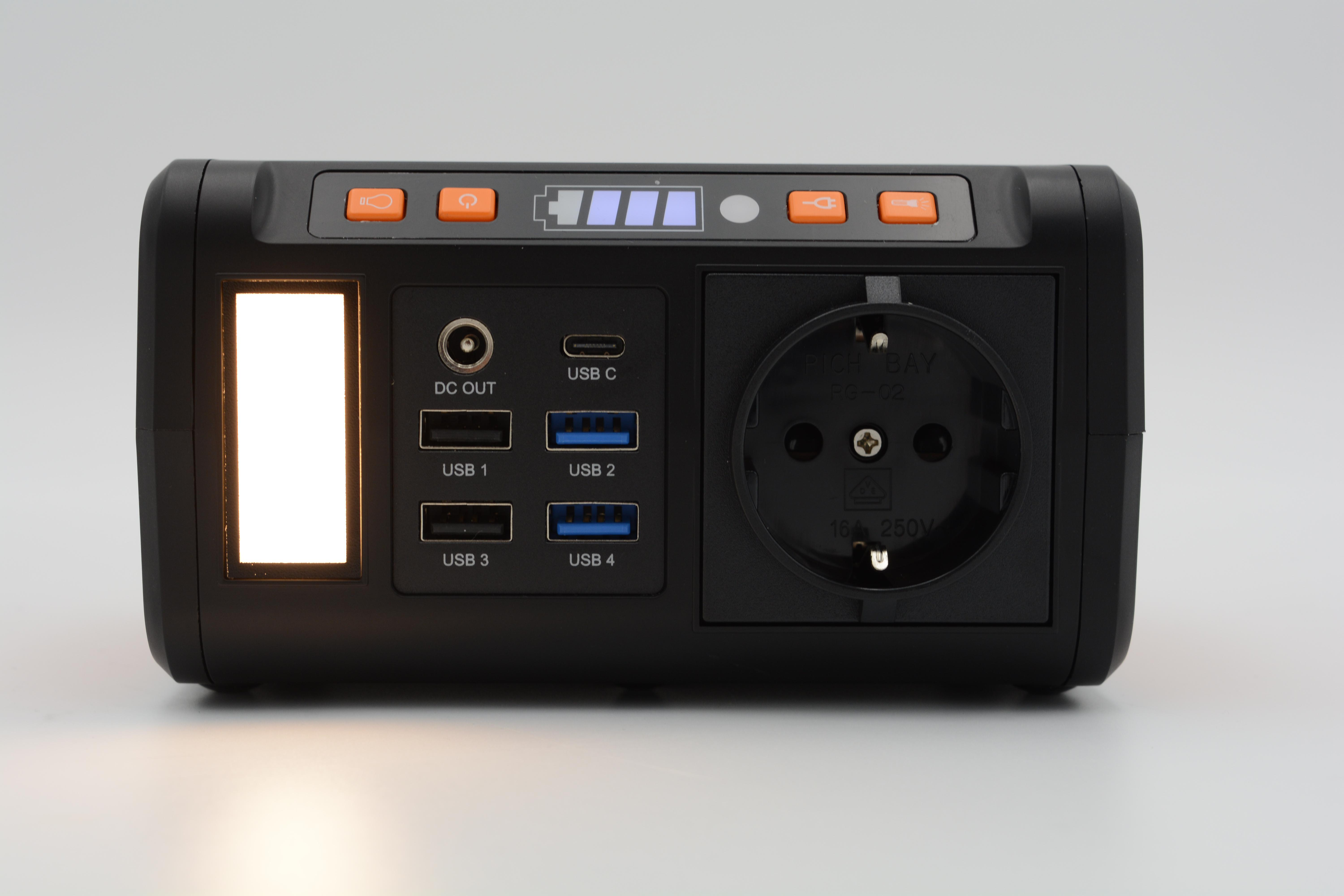 Schwarze Powerstation mit mehreren USB-Anschlüssen, einem Licht und einer Steckdose. Sie hat eine orangefarbene Taste.