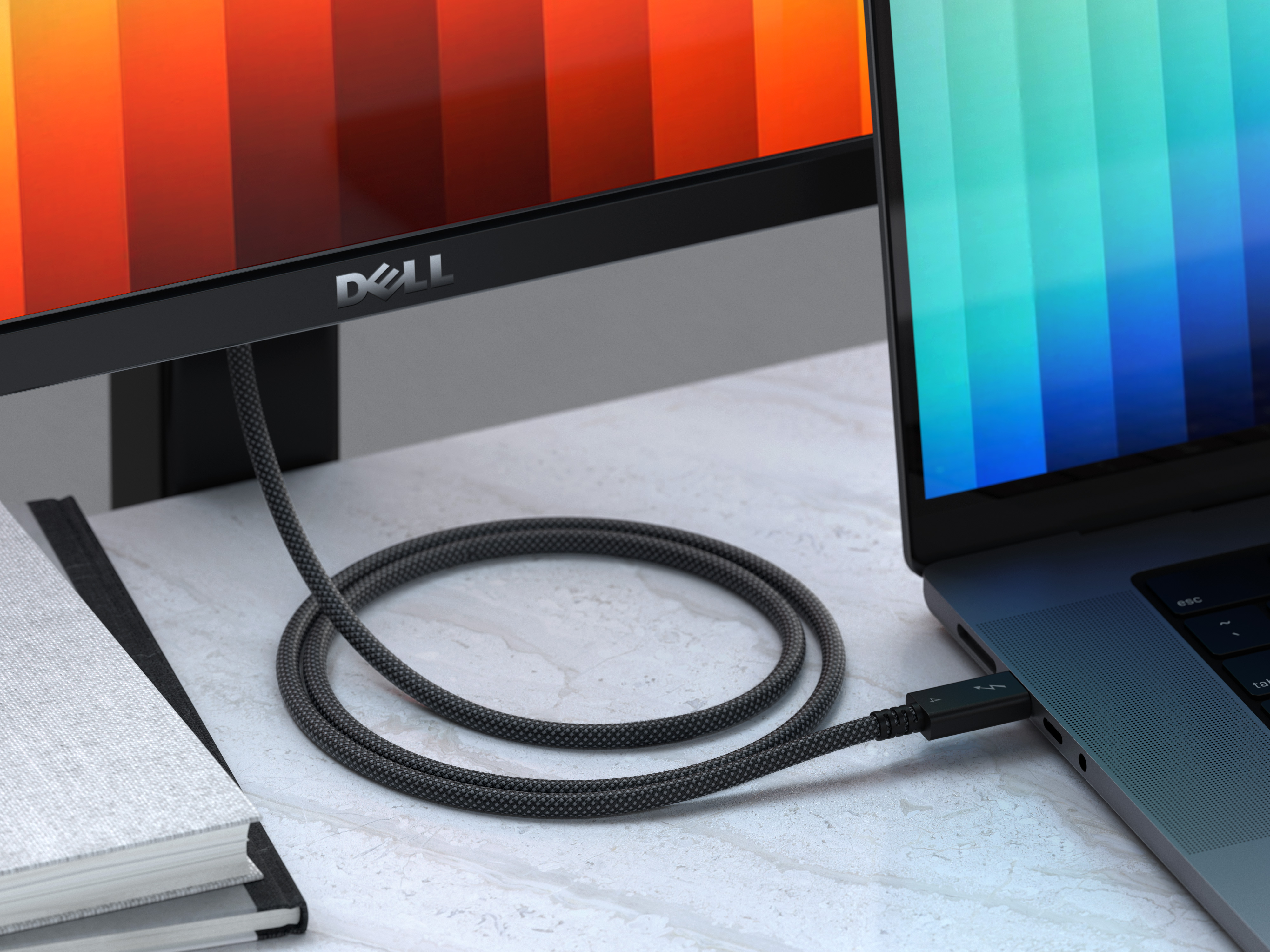 Egy laptop egy monitorhoz csatlakoztatva kábellel. A kábel szürke, a monitor színes képet mutat.