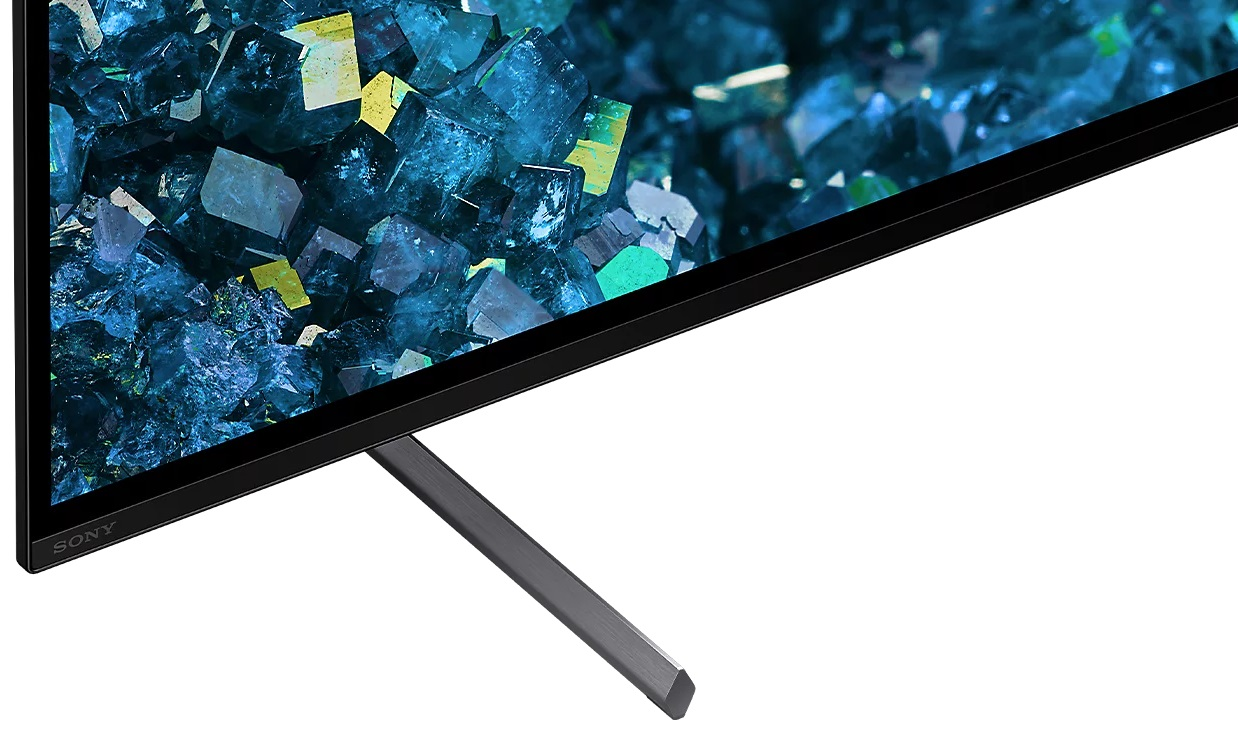 Zbliżenie telewizora, czarna ramka, podparta srebrną nogą, z krystalicznym tłem.