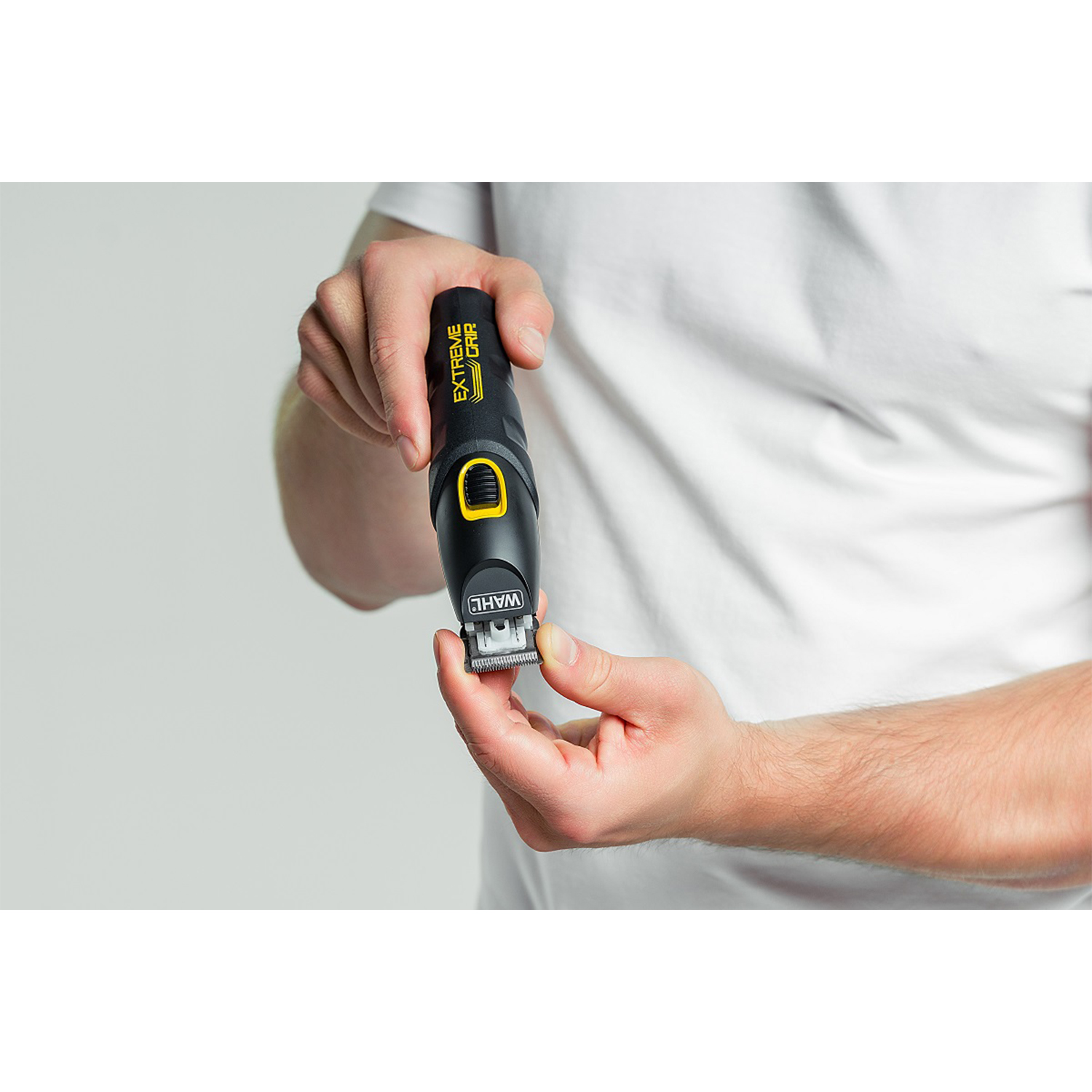 Uomo che tiene un trimmer Wahl Extreme Grip, mostrando la lama, su sfondo bianco.