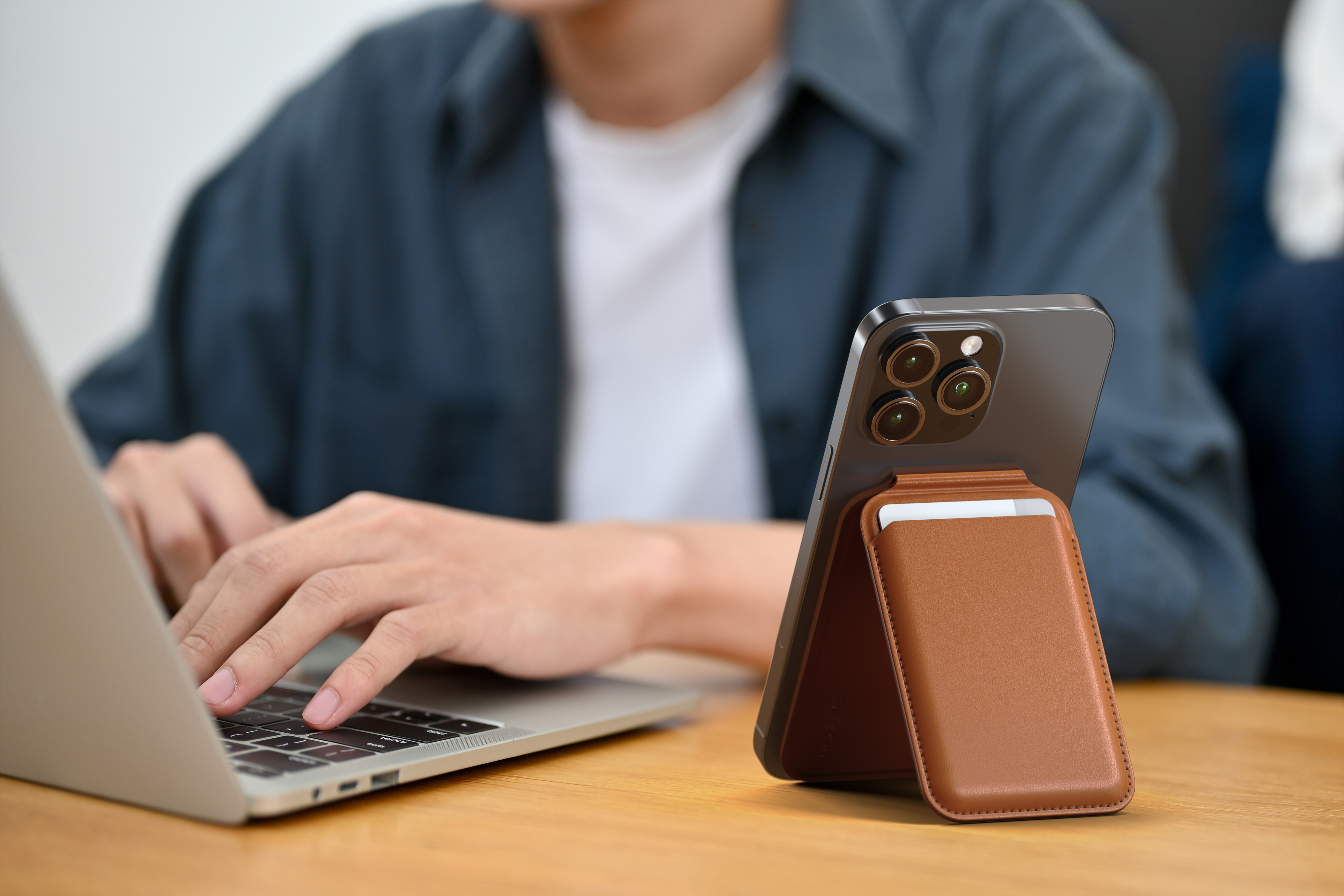 Személy laptopot használ telefonnal és bőr állvánnyal. A telefon kamerát mutat.